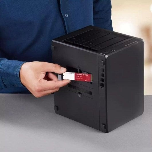 Un uomo inserisce un SSD WD Red SN700 rosso in un dispositivo NAS nero.