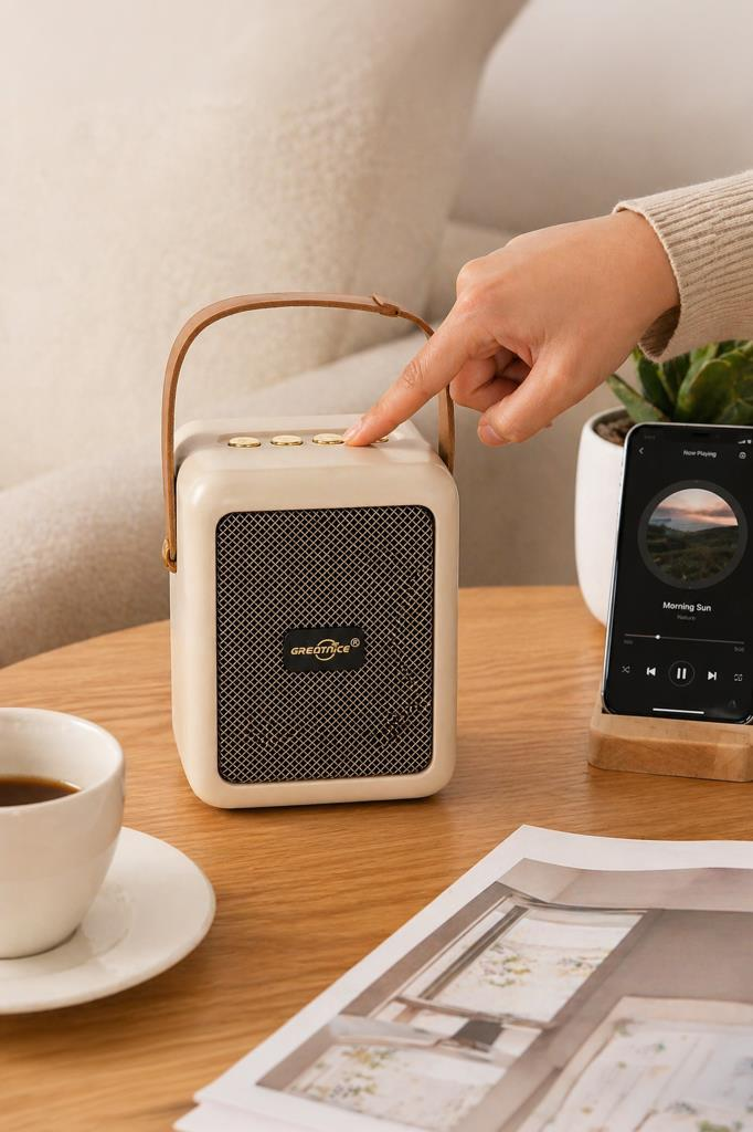 Bir el krem rengi hoparlöre basıyor. Bir telefon Müzik çalıyor.