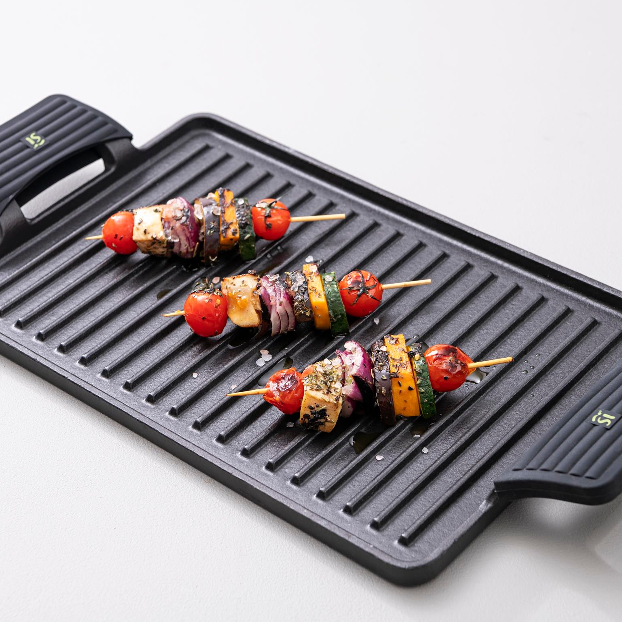 Tres brochetas de verduras con tomates, calabacín y berenjena en una sartén.