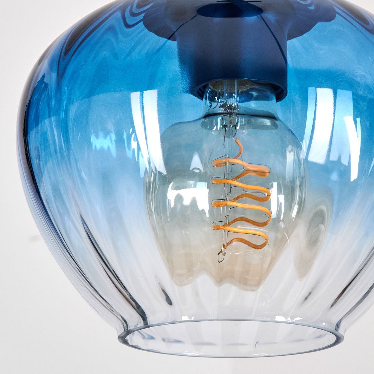 Eine blaue Glaslampe mit einer Glühbirne mit orangefarbenem Glühdraht.