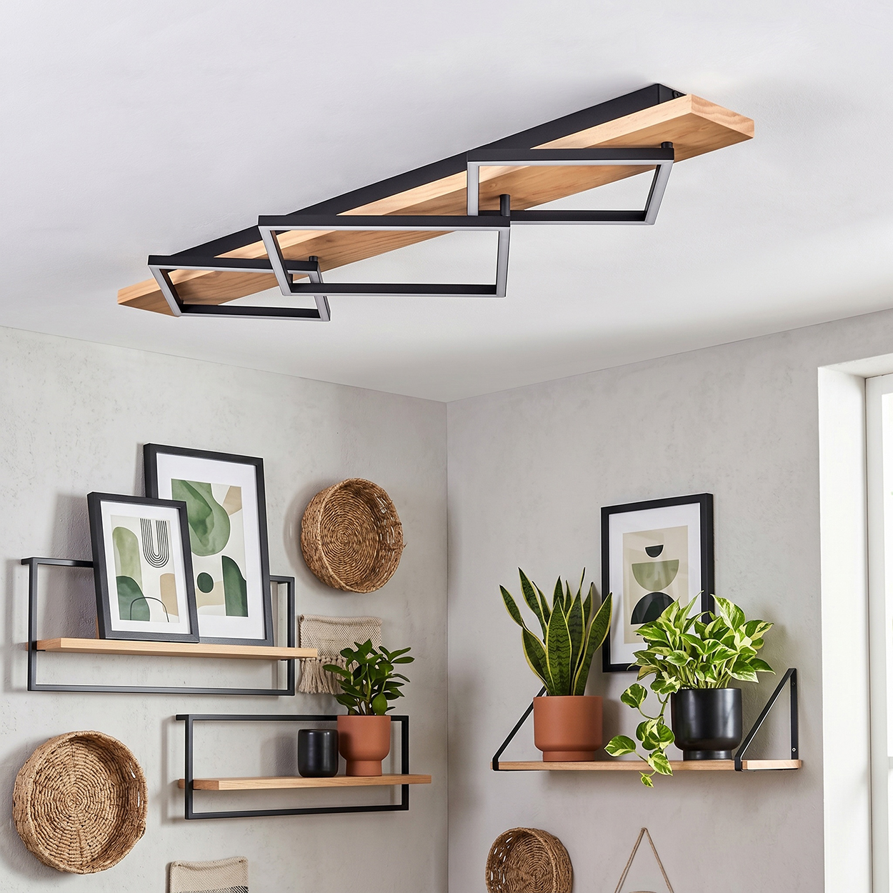 Holzregale mit Pflanzen, Bildern und Körben an einer grauen Wand.