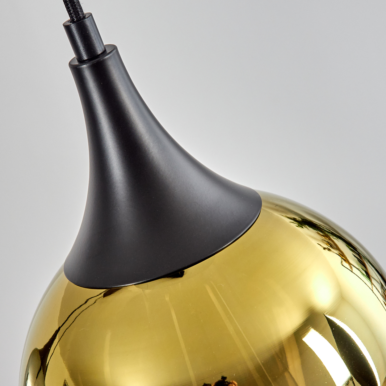 Ein goldener Pendelleuchter mit schwarzem Baldachin.