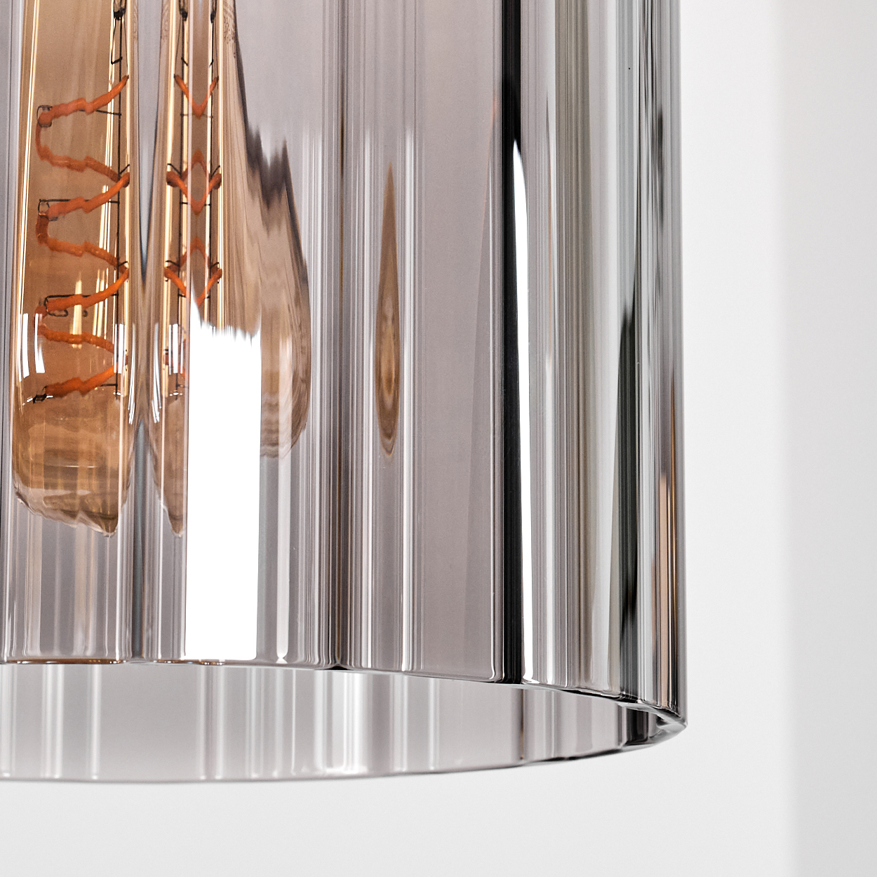 Glühbirne mit Spiralwendel hinter geriffeltem Glaszylinder, Nahaufnahme.