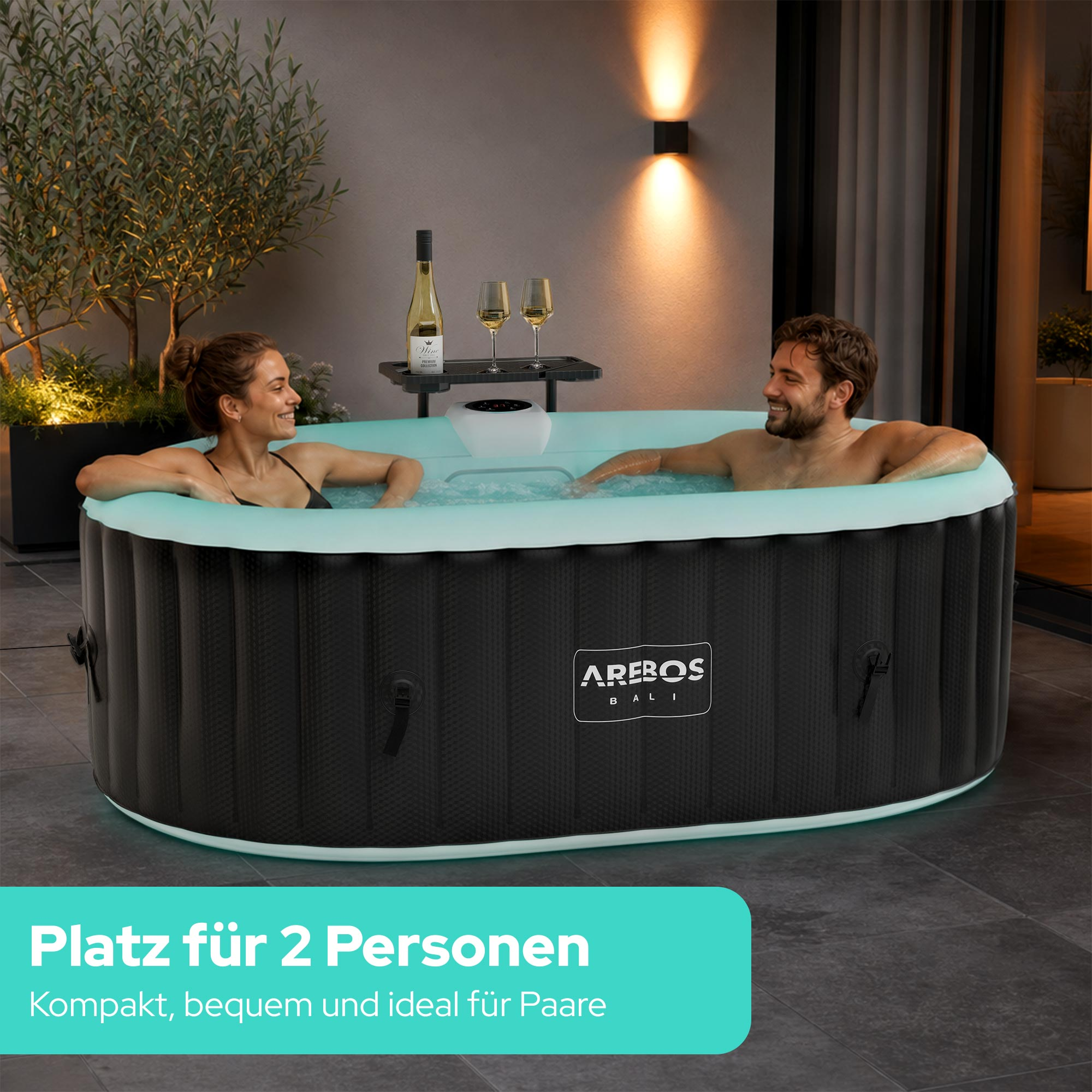 Ein Paar entspannt in einem aufblasbaren Whirlpool bei Nacht mit beleuchtetem Baum.