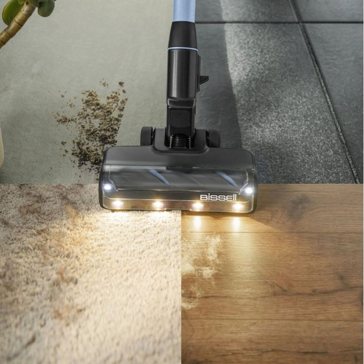 Ein Bissell-Staubsaugerkopf reinigt Schmutz von Teppich und Holzboden. Lichter leuchten.