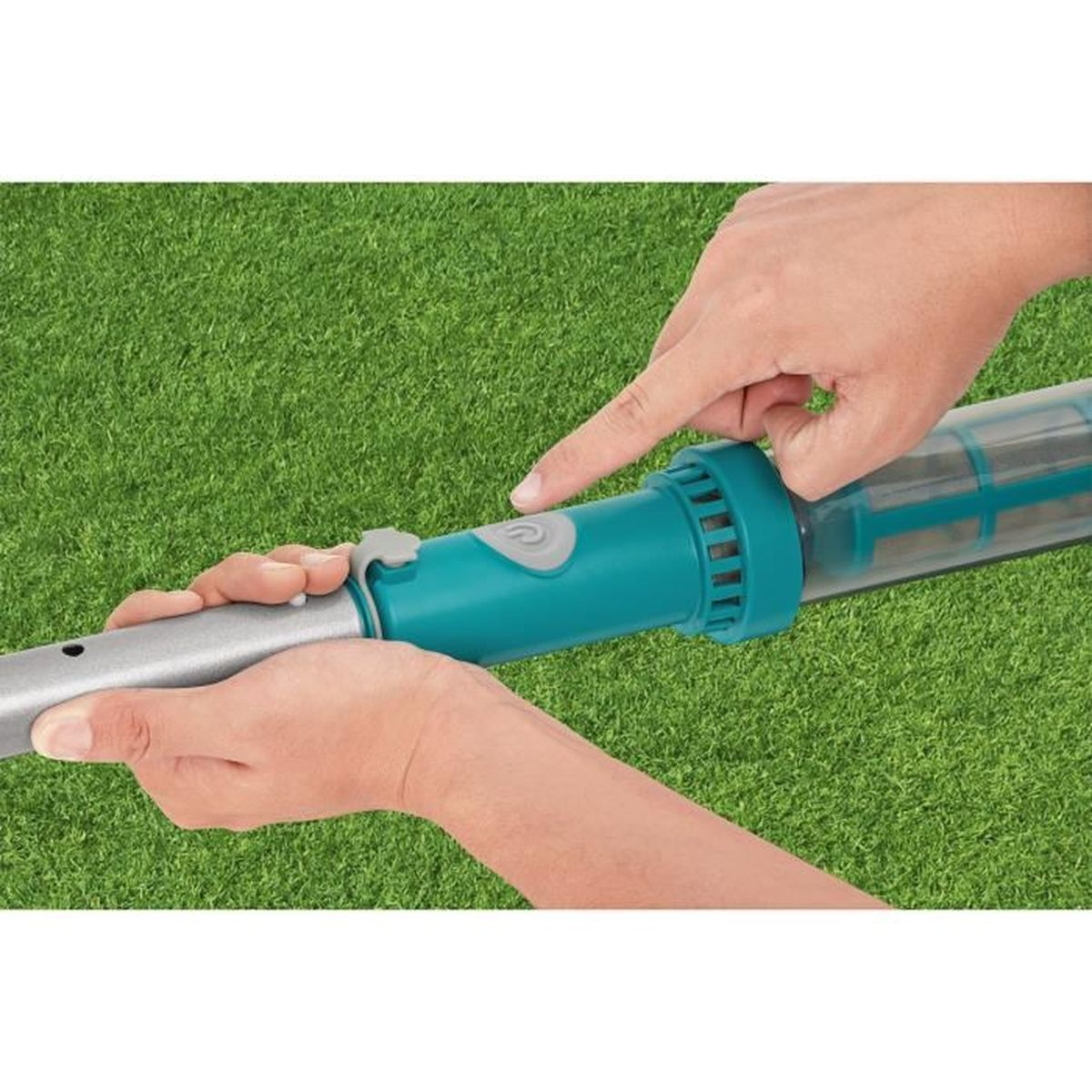 Hände halten einen tealfarbenen Stab mit einem Knopf. Gras im Hintergrund.