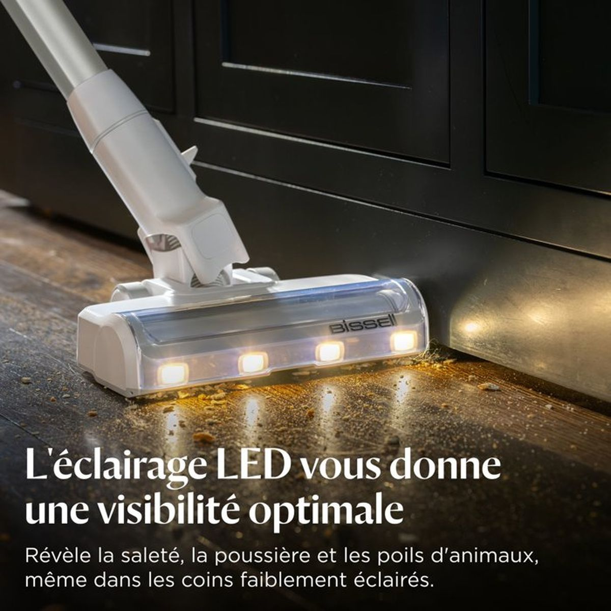 Ein weißer Staubsaugerkopf mit LED-Lichtern reinigt einen staubigen Holzboden.