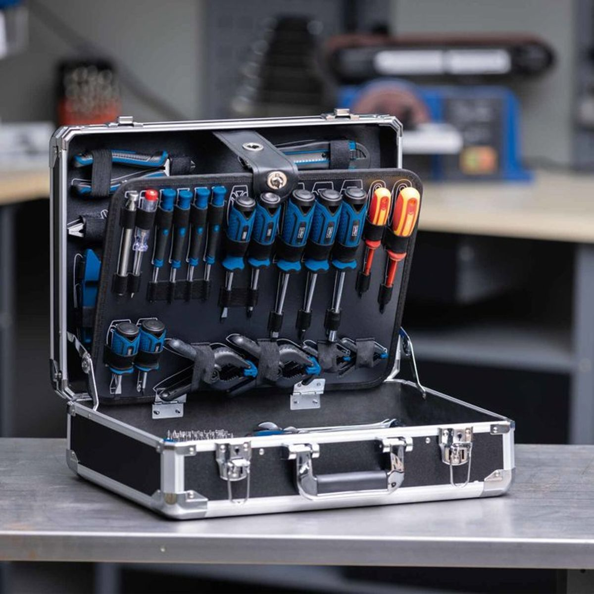 An open toolbox with screwdrivers and pliers on a workbench.