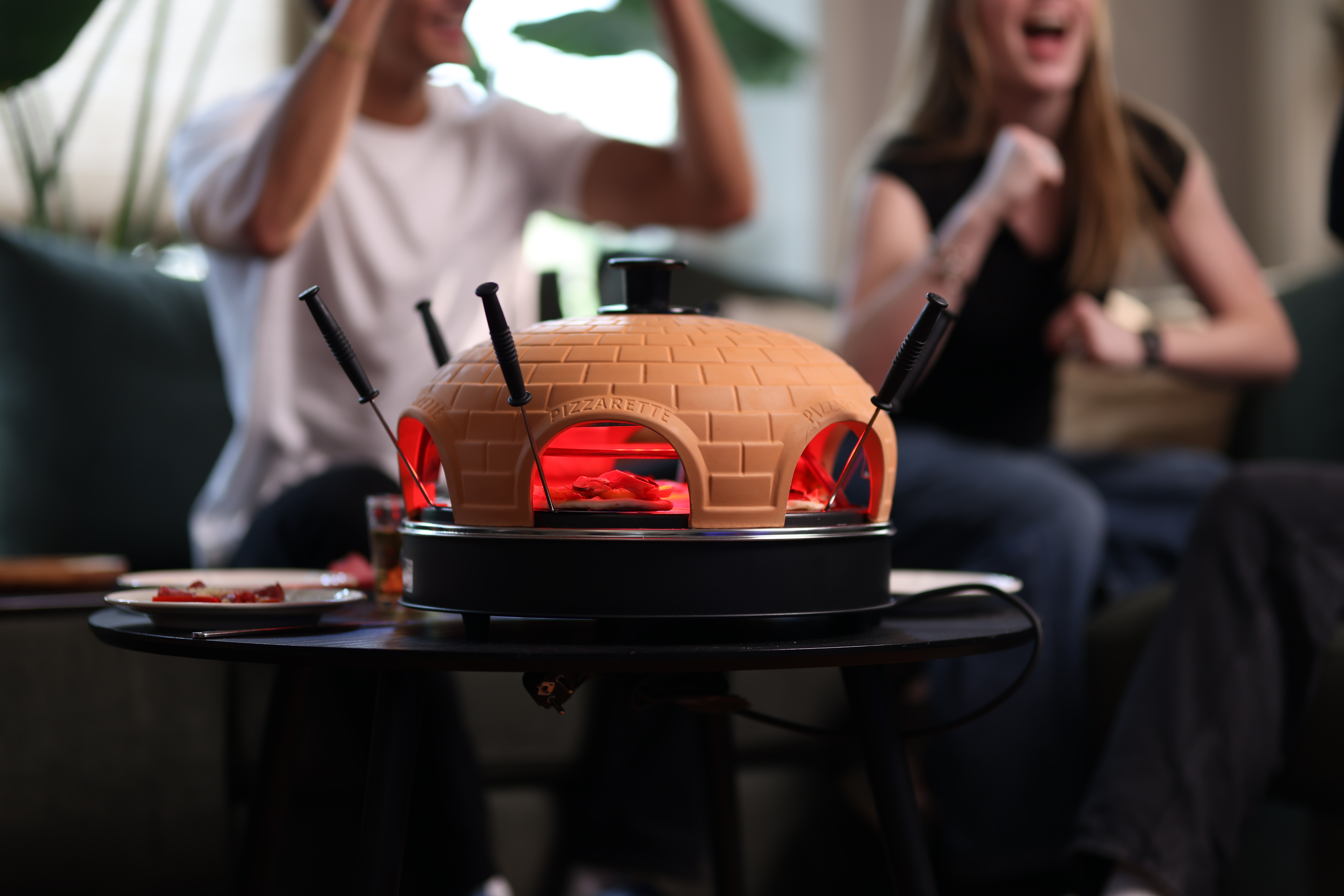 Een pizzaoven op tafel met mensen op de achtergrond.