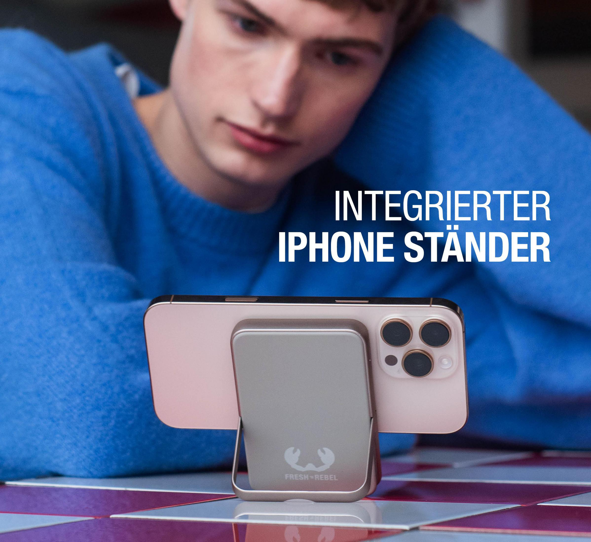 Un uomo con maglione blu guarda un telefono con supporto integrato.