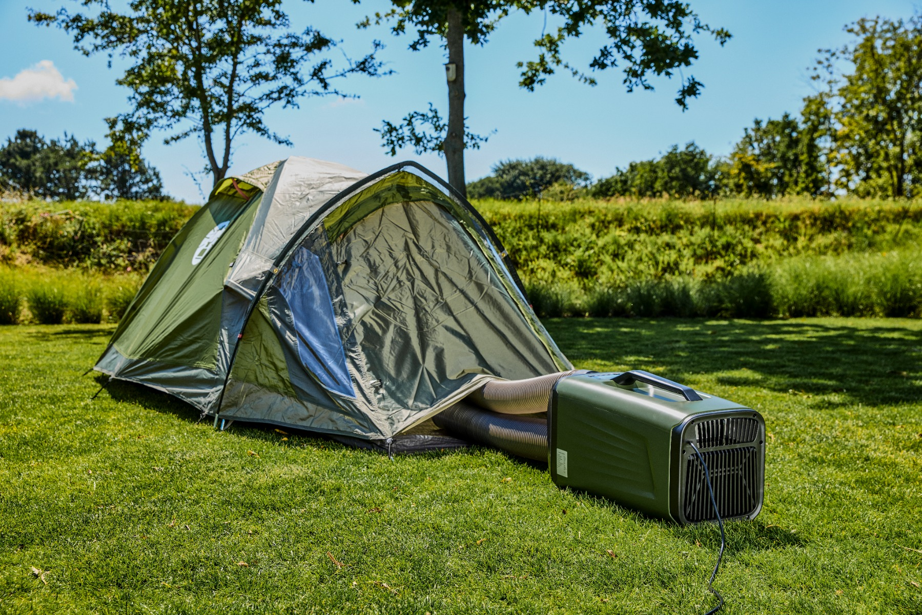 Una tenda verde sull'erba con una stufa collegata tramite tubi.