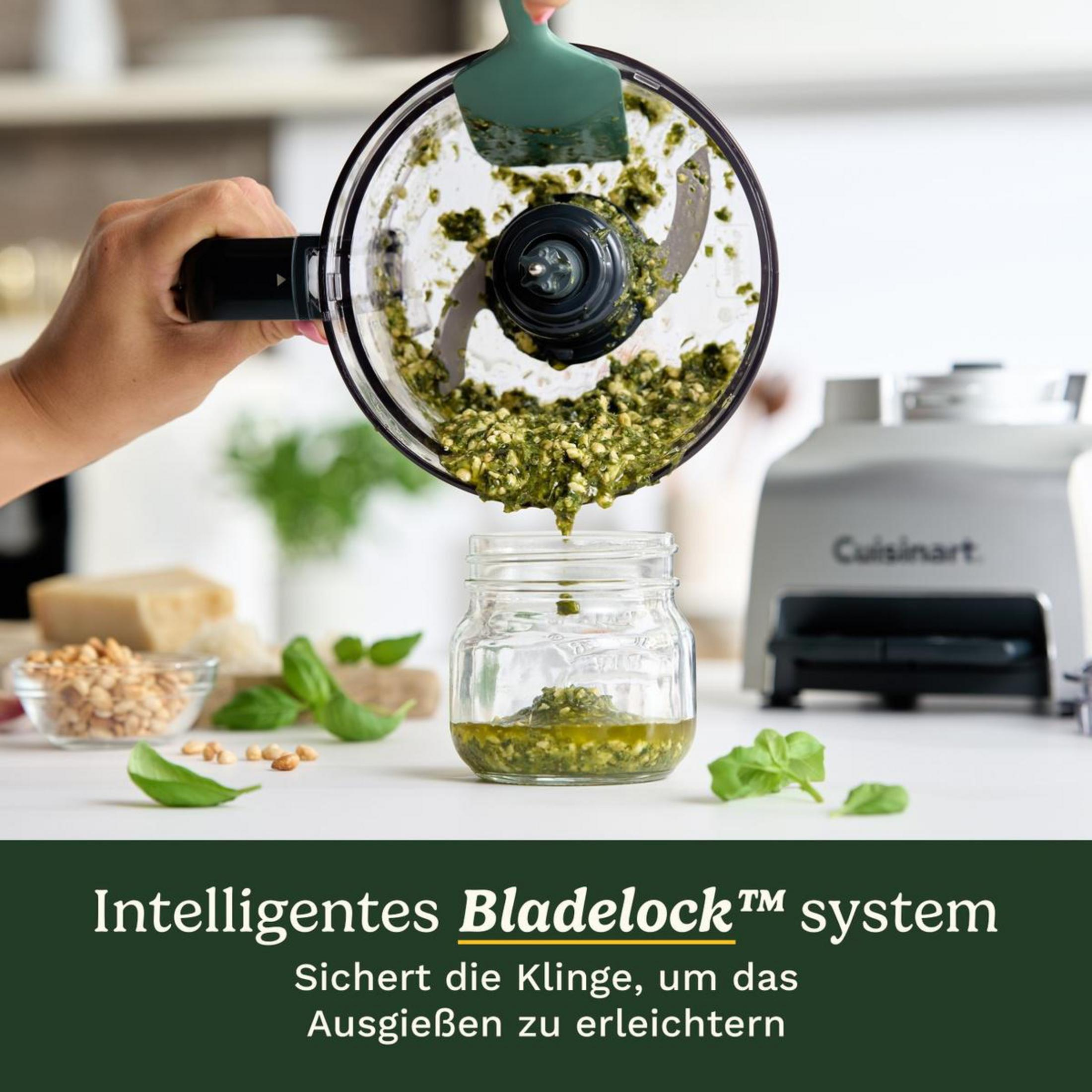 Il pesto viene versato da un robot da cucina in un barattolo. Ingredienti nelle vicinanze.