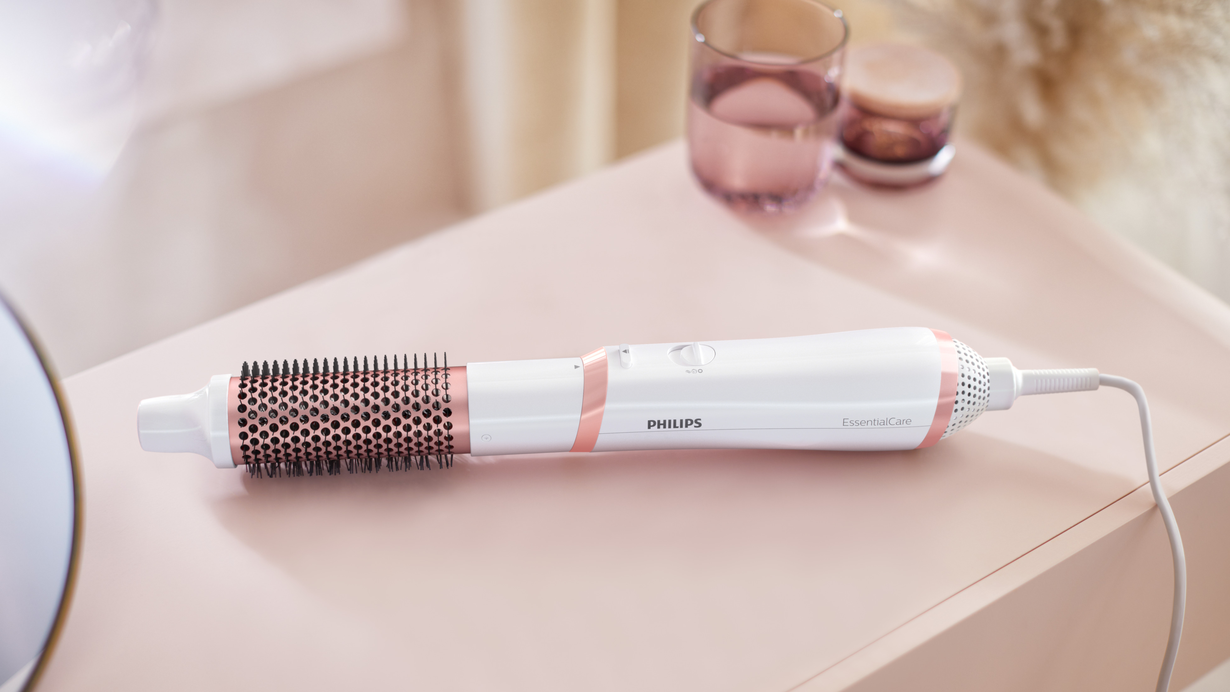 Un'asciugacapelli Philips bianca con accenti oro rosa su una superficie rosa.
