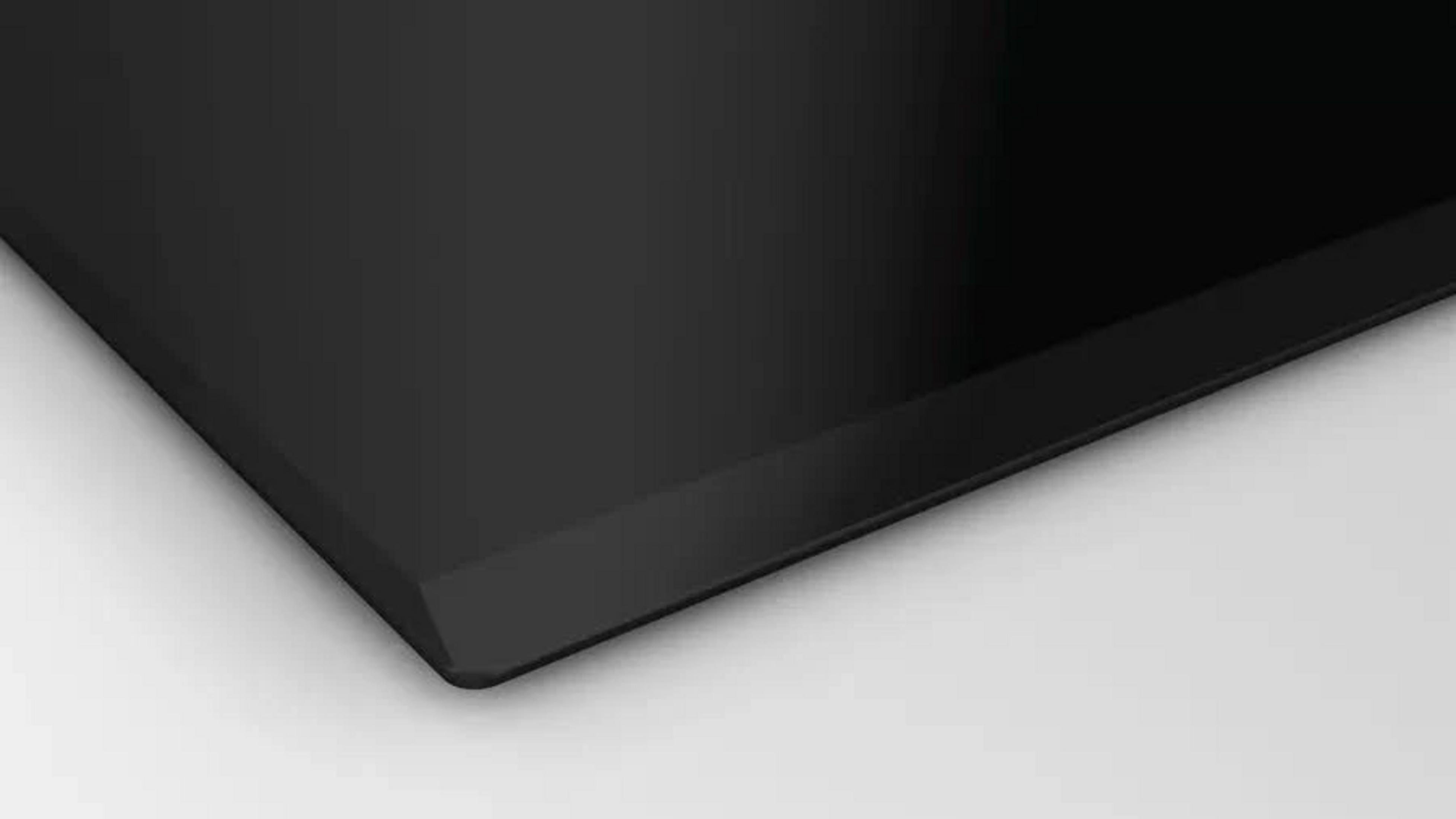 Primer plano del borde de una placa de cocina negra sobre fondo blanco.
