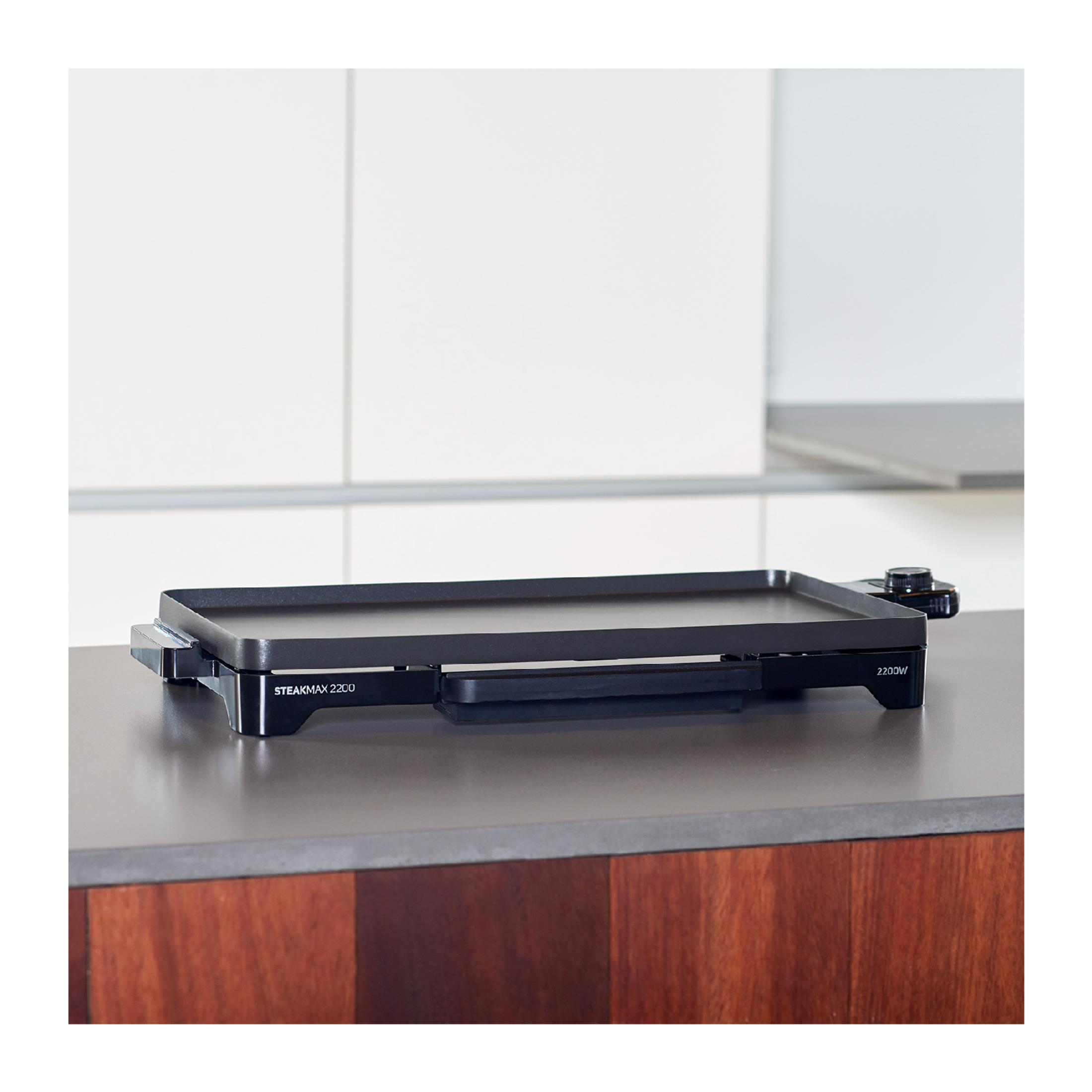 Eine schwarze elektrische Grillplatte mit Steakmax 2200 und 2200W Aufschrift.
