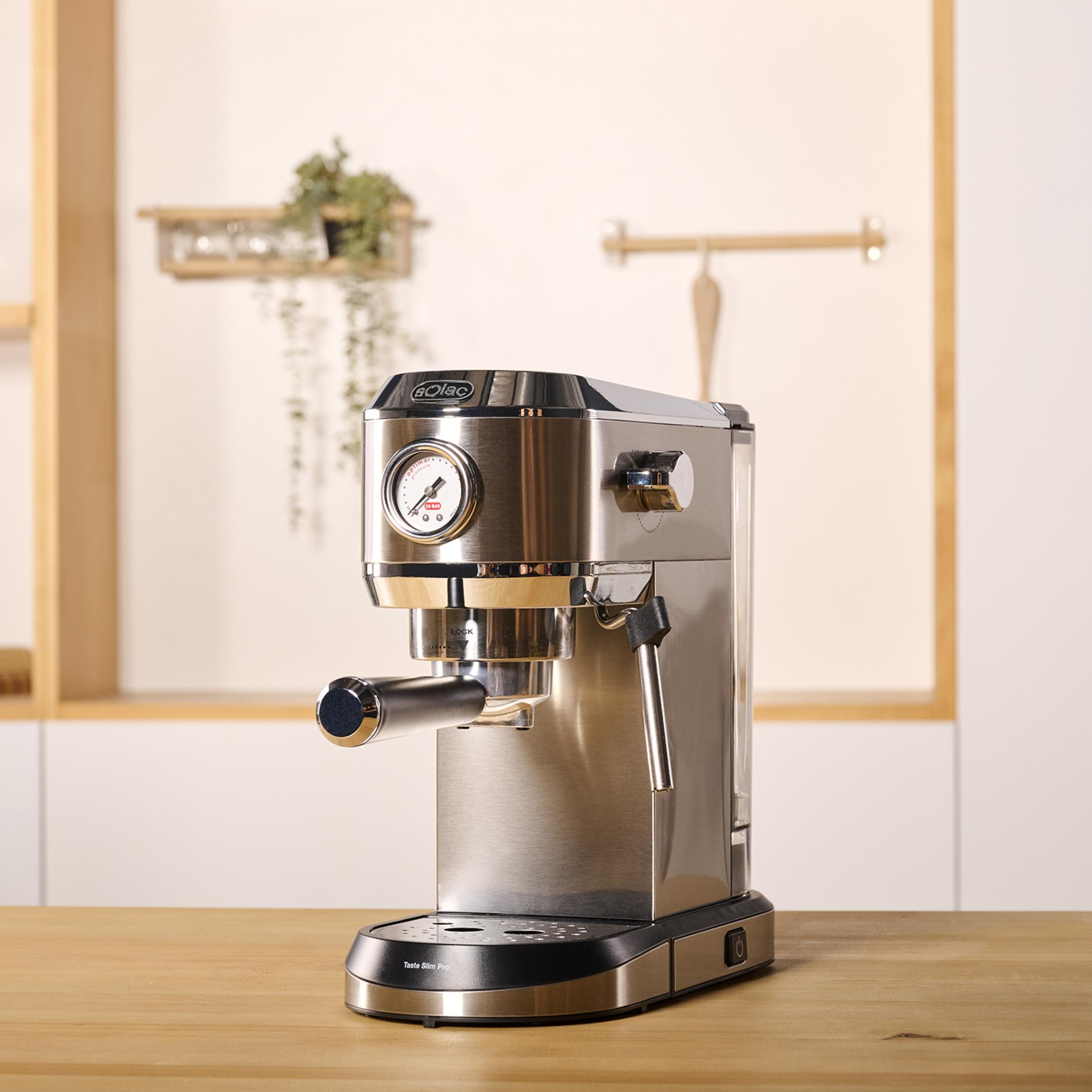 Una máquina de espresso plateada con manómetro está sobre una mesa de madera.