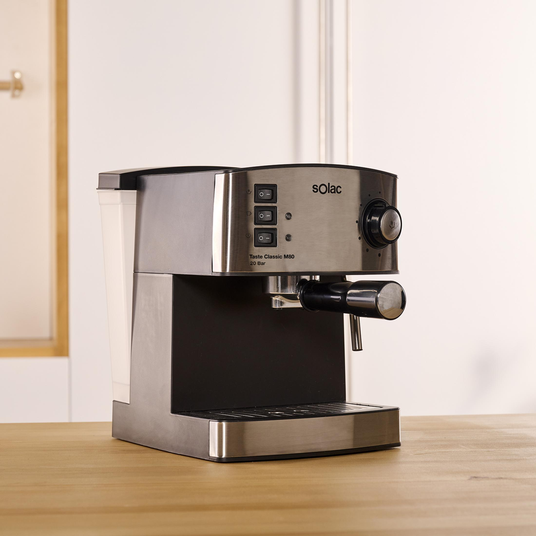 Una máquina de espresso plateada y negra sobre una mesa de madera.