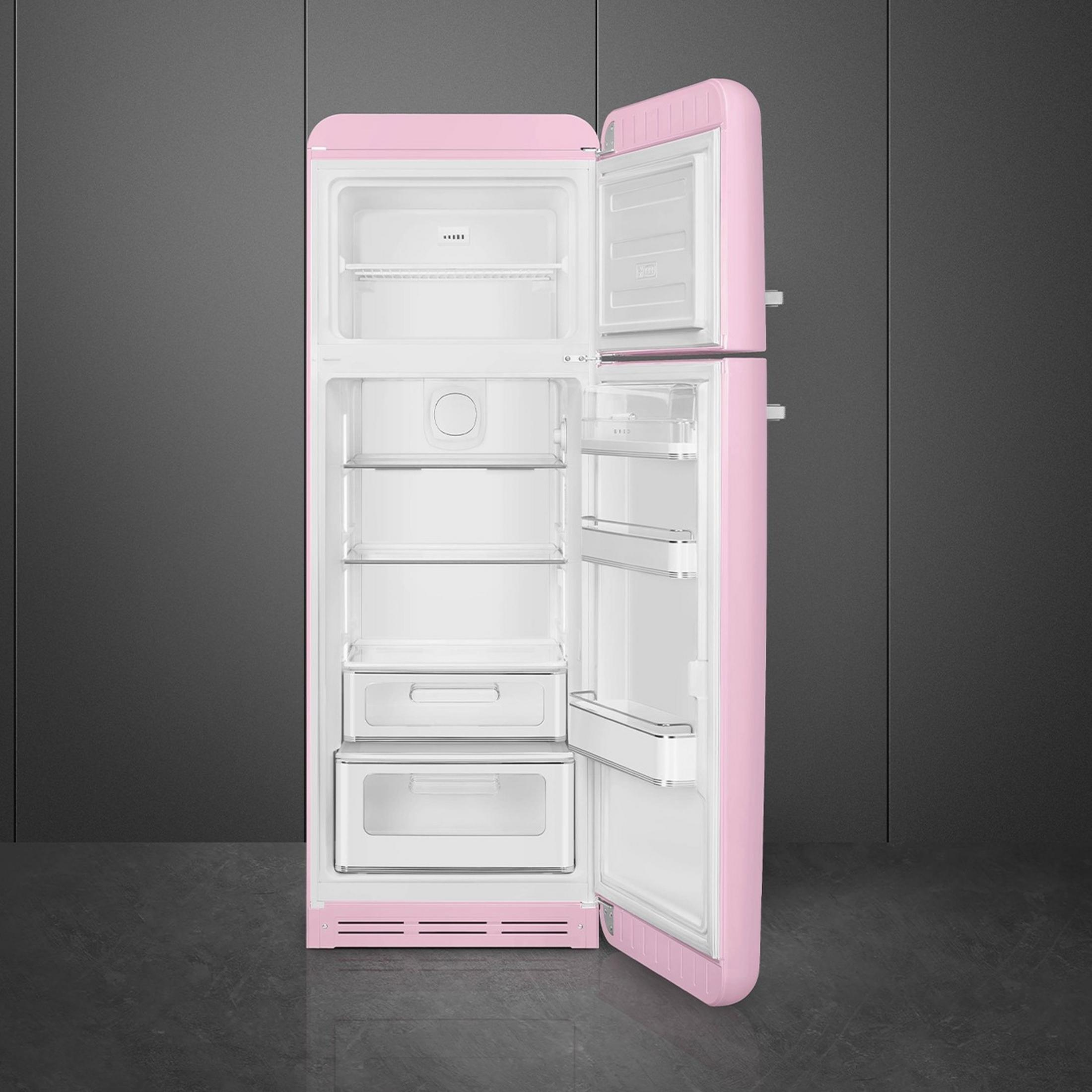 Refrigerador retro rosa abierto con estantes y cajones sobre fondo oscuro.
