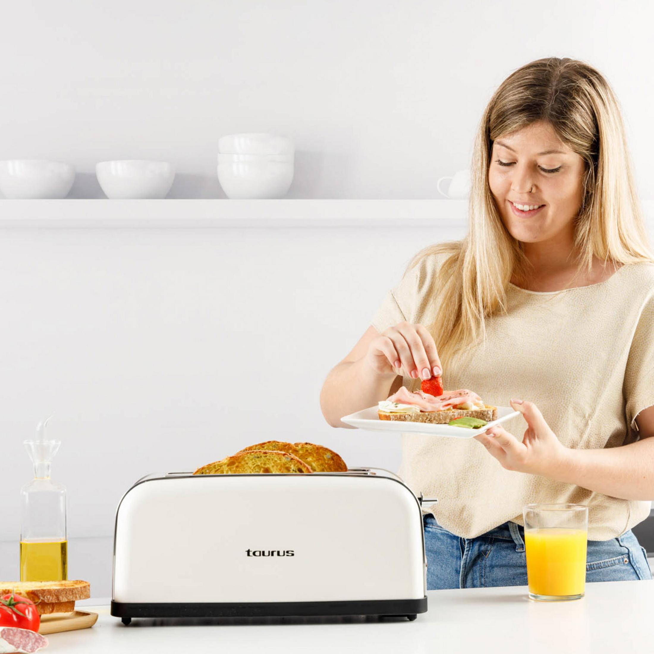 Una donna guarnisce un panino con fragole accanto a un tostapane e succo.