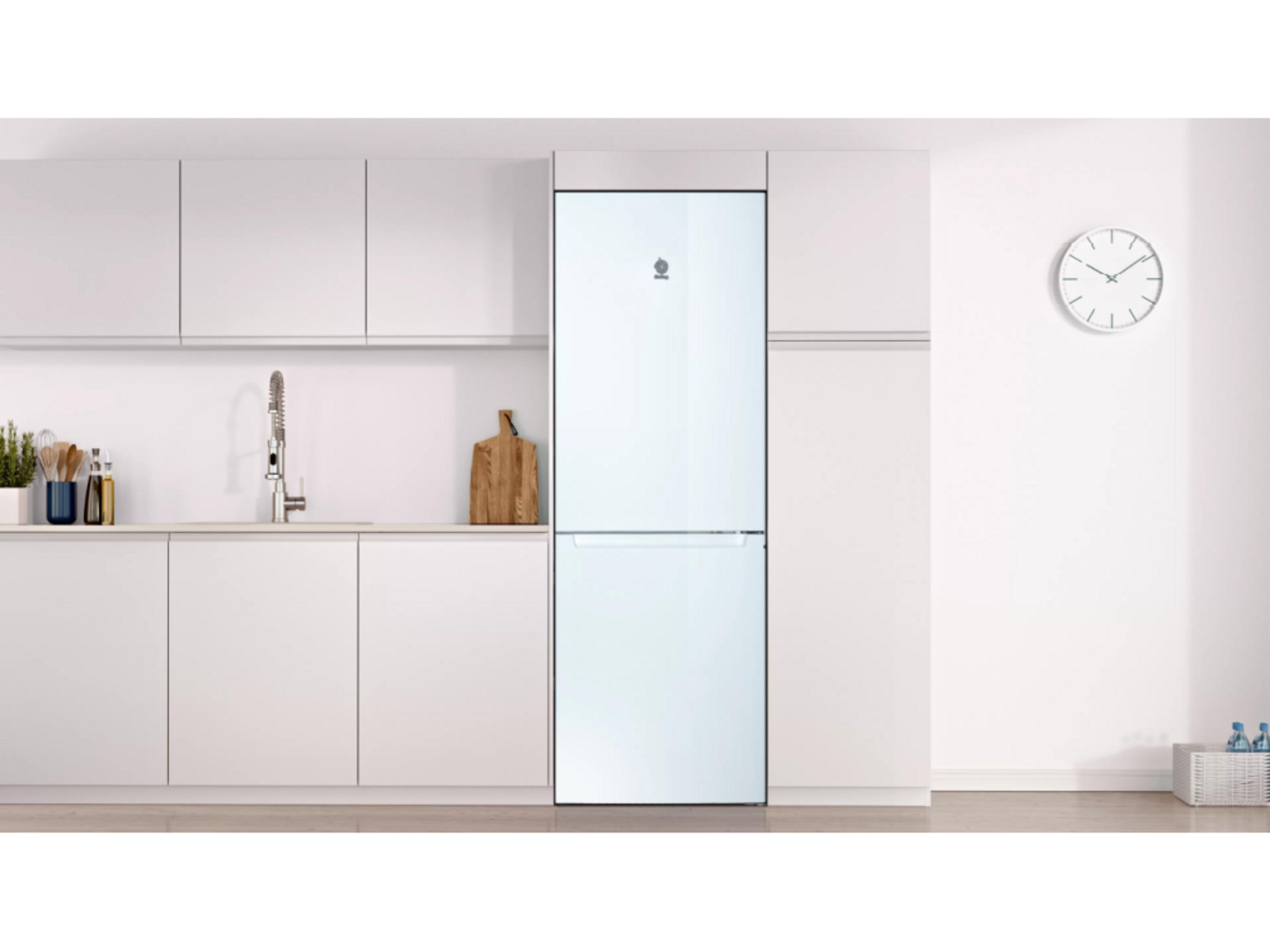 Encimera de cocina blanca con frigorífico, fregadero y reloj.