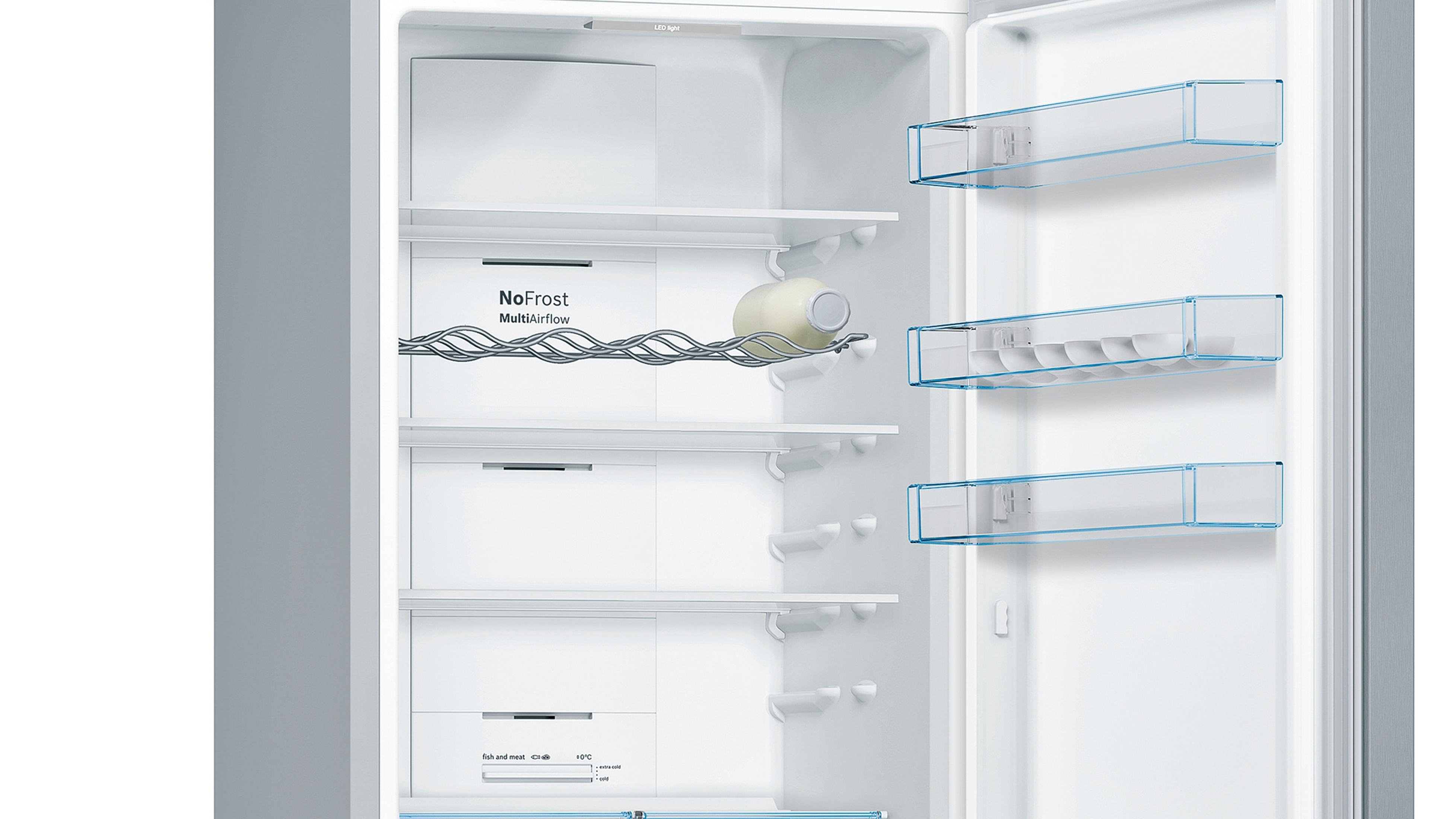 Interior de un refrigerador blanco con estantes y cajones. Una botella descansa en una rejilla.