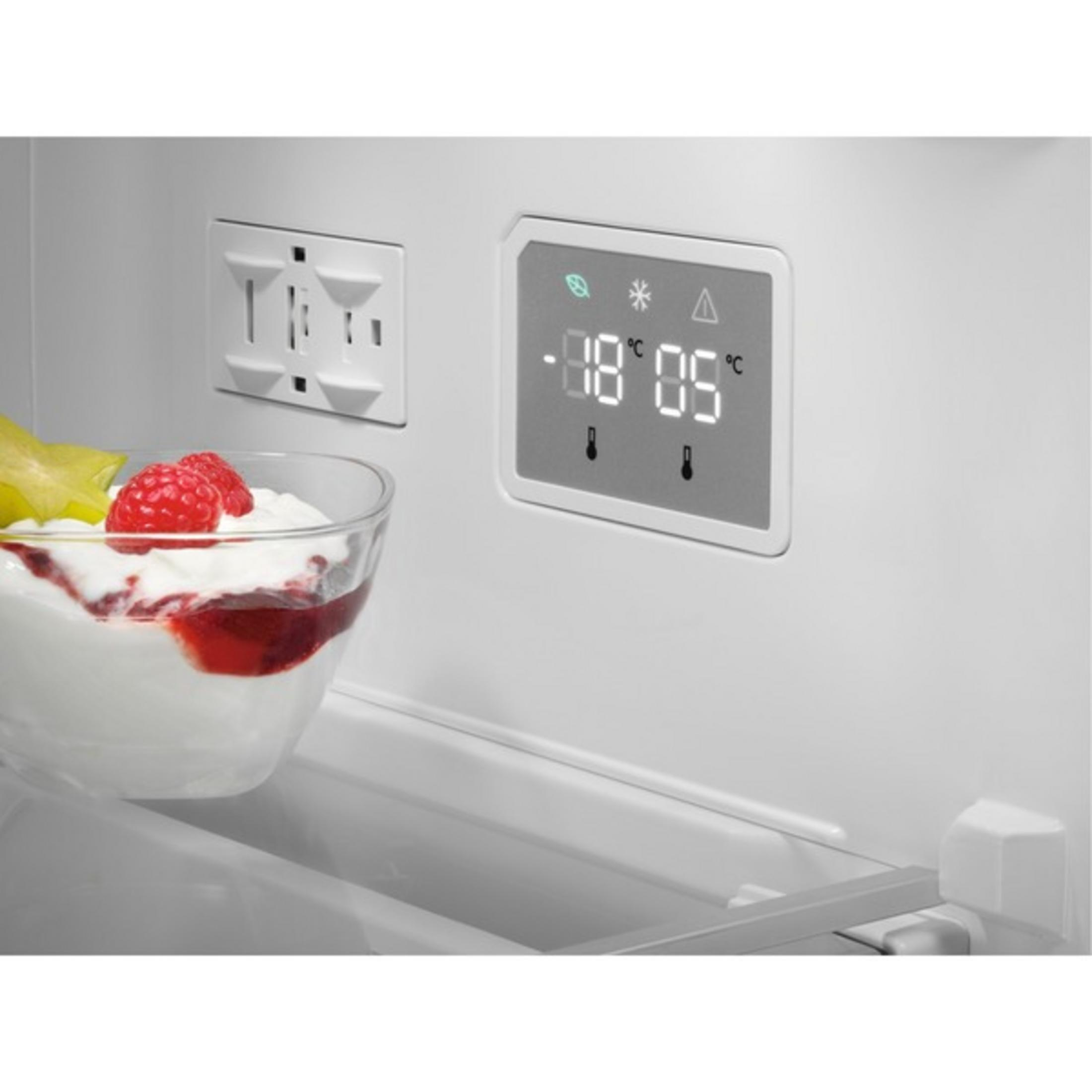 Primer plano de un tazón de yogur con frambuesas y carambola, junto a una pantalla digital.