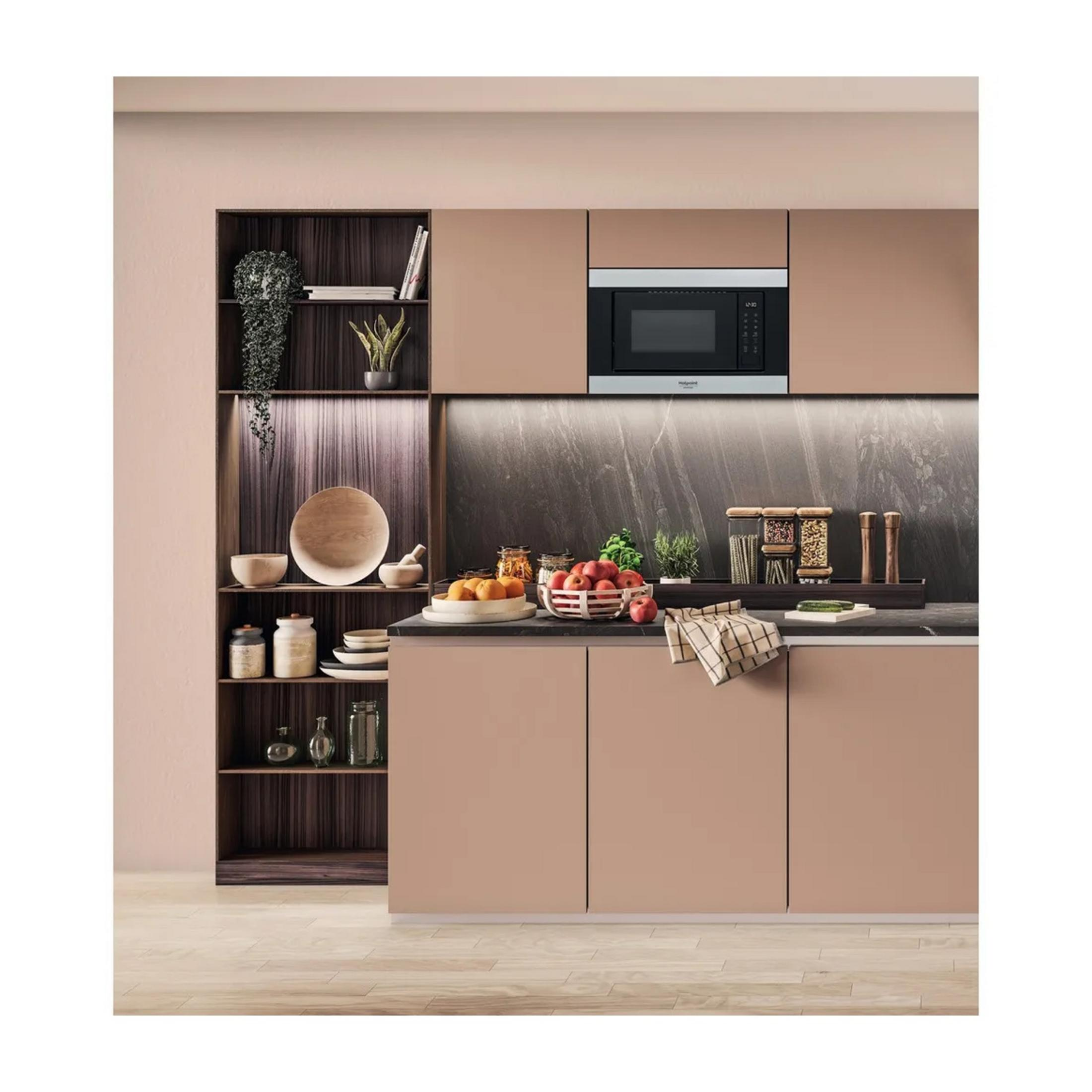 Cocina moderna con microondas, frutas y platos en encimera y estantes.