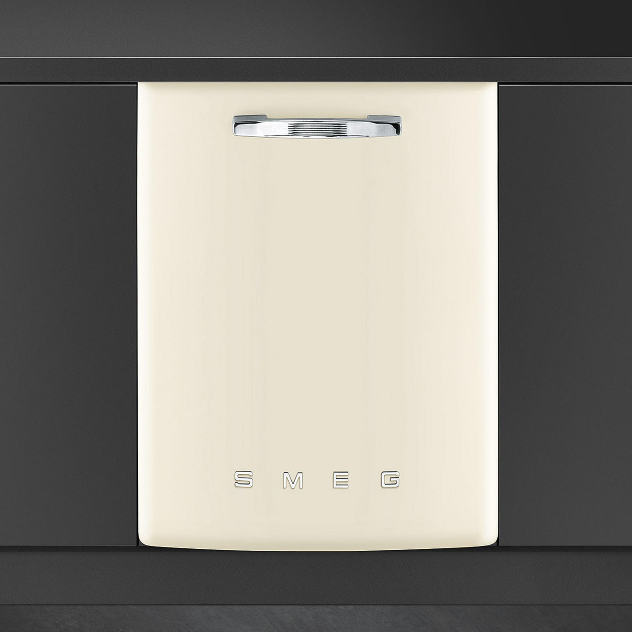 Una lavastoviglie Smeg color crema con maniglia e logo argentati, su ante scure.