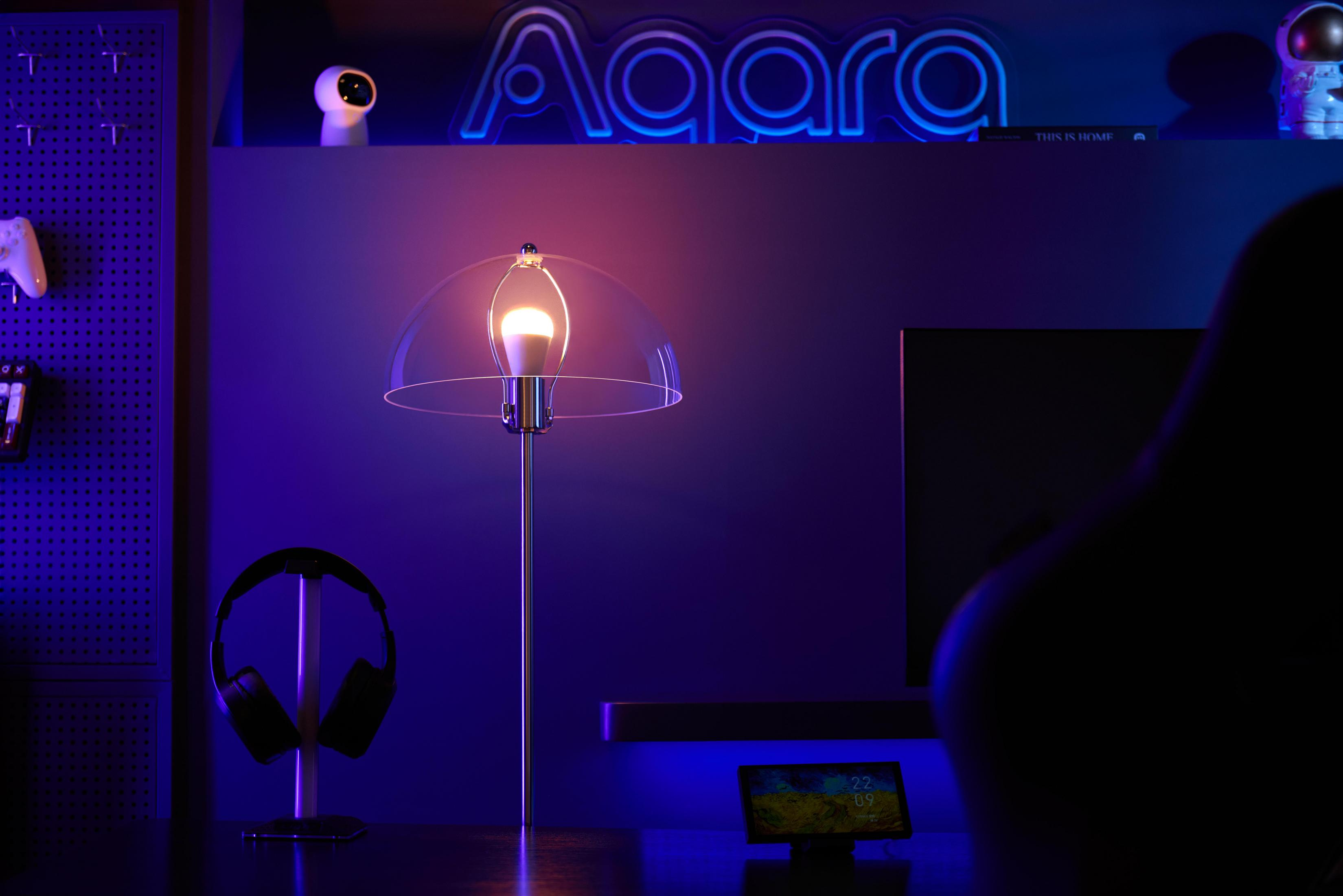 Ein Nachttisch mit Lampe, Kopfhörern, Controller und einem kleinen Bildschirm.