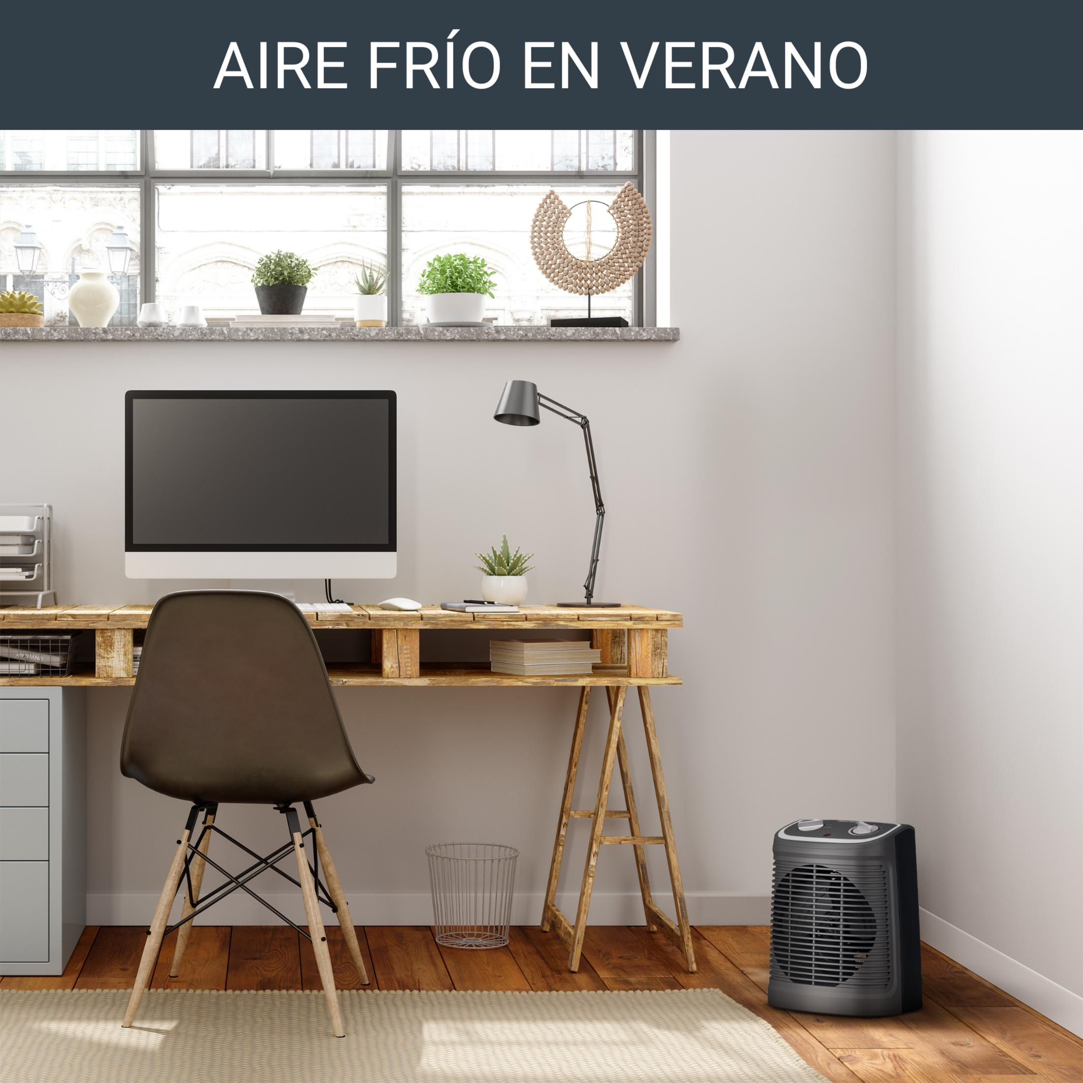 Un bureau avec un ordinateur, une chaise et un radiateur soufflant près d'une fenêtre.