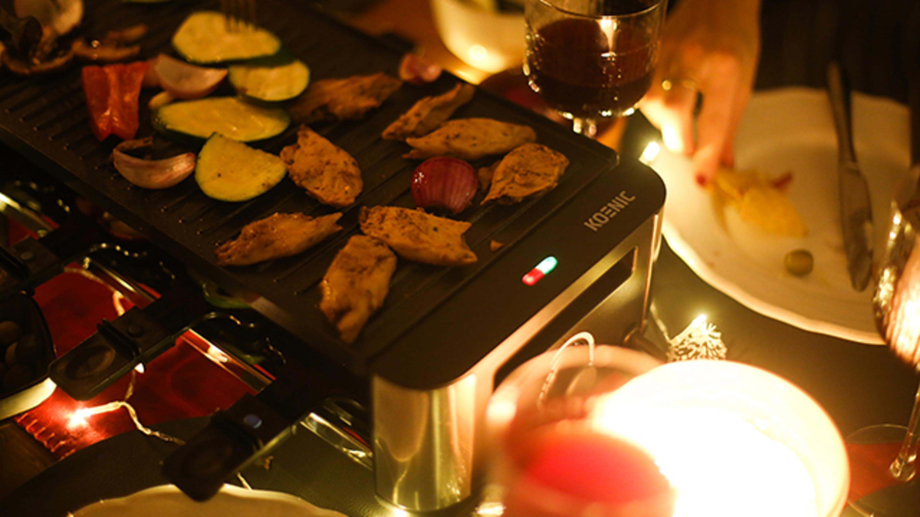 Essen gart auf einem Raclette-Grill: Zucchini, Paprika, Zwiebeln und Hähnchen.