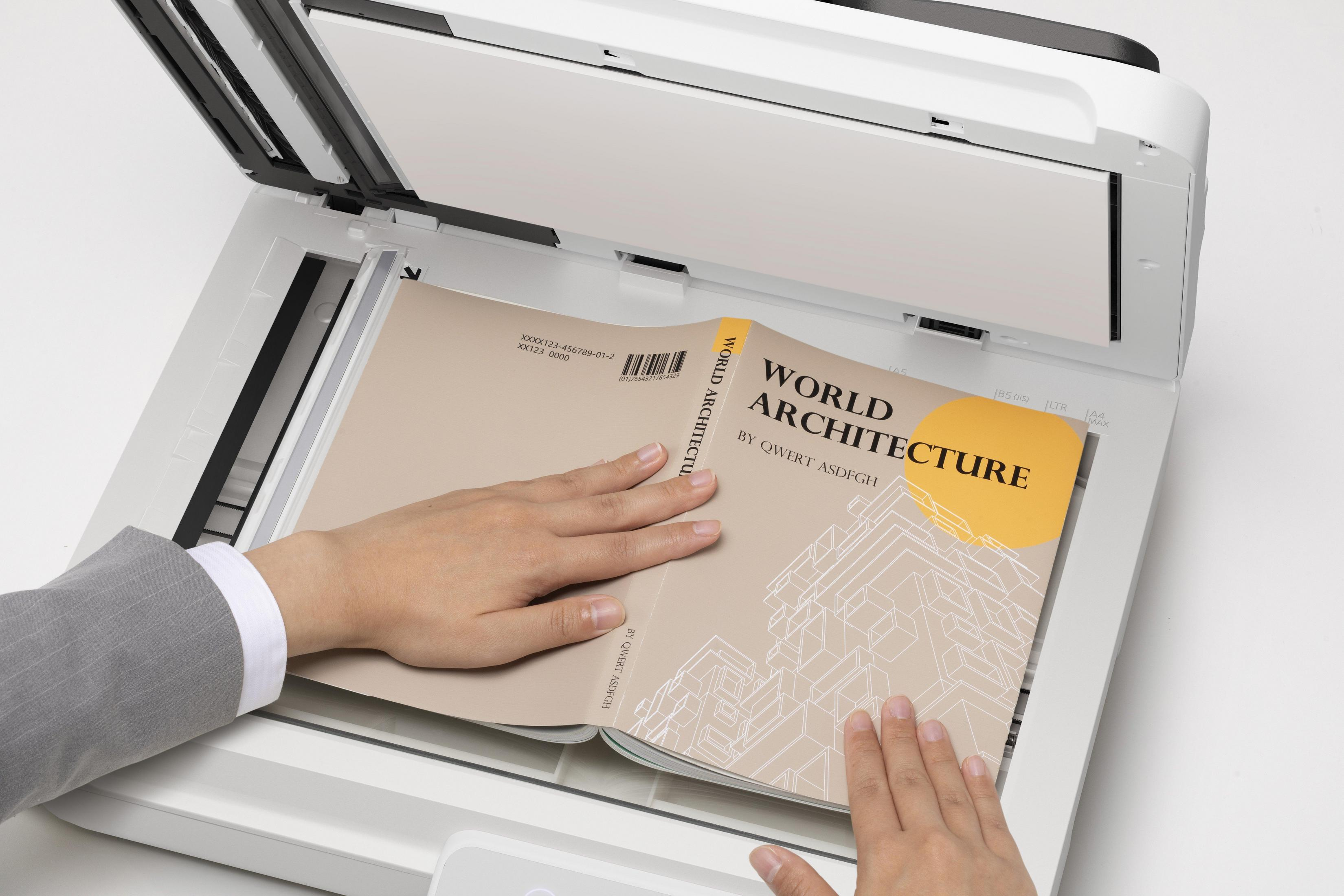 Hands on a book titled 'World Architecture' on a scanner.