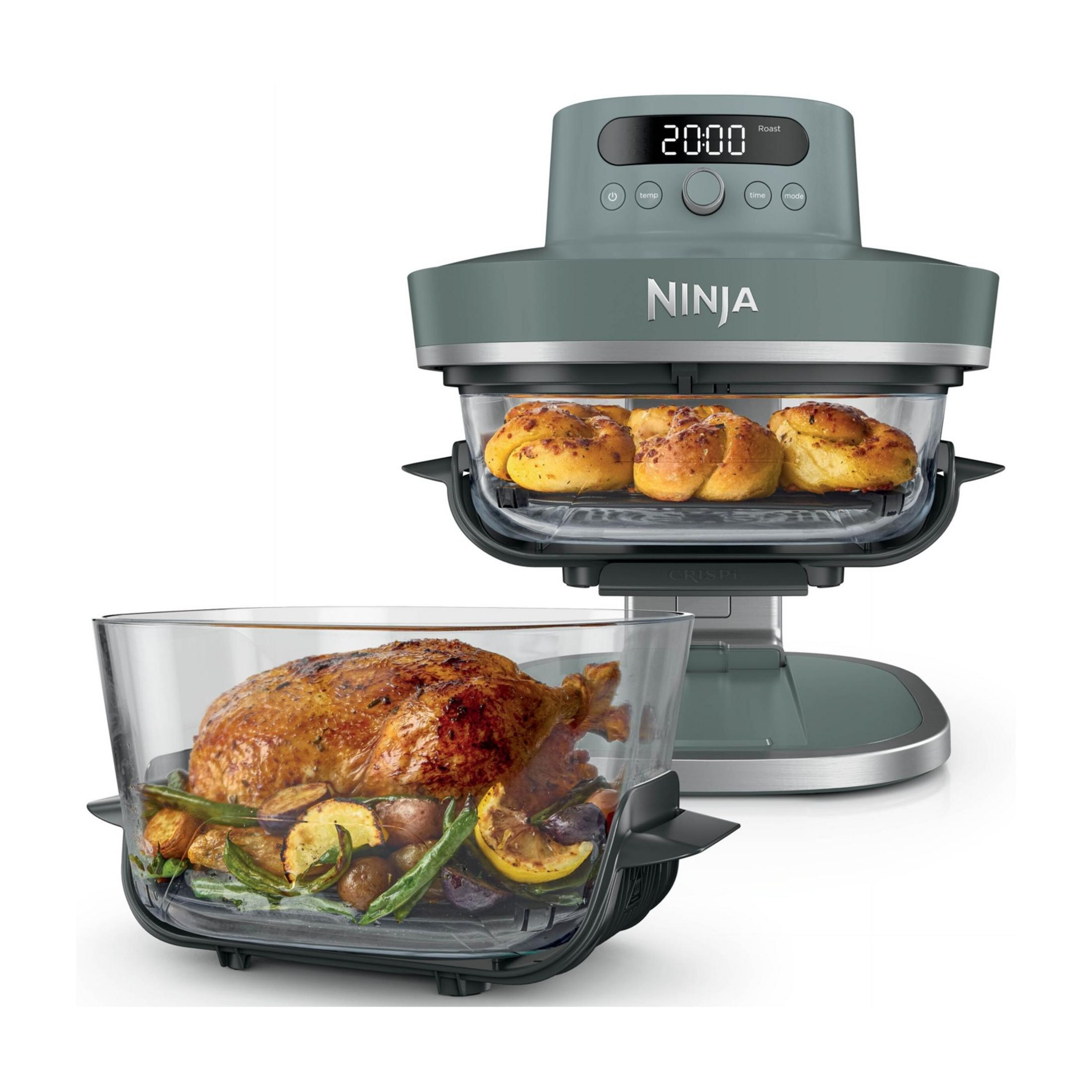 Un four Ninja gris avec du poulet rôti et des légumes dans un plat en verre.