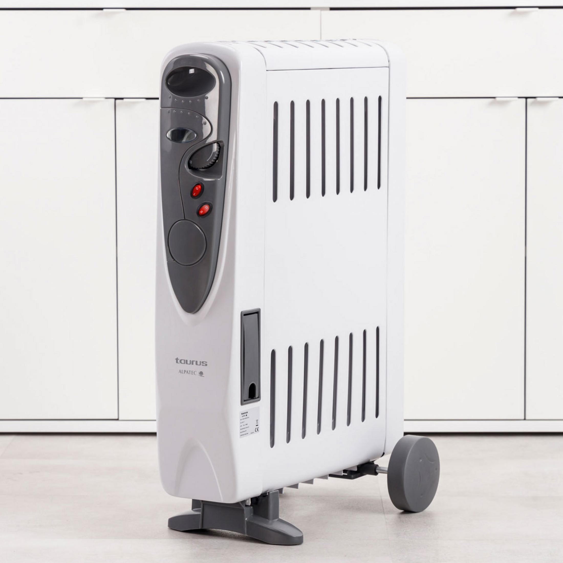 Ein weißer Ölradiator mit Rädern und Bedienelementen steht vor weißen Schränken.