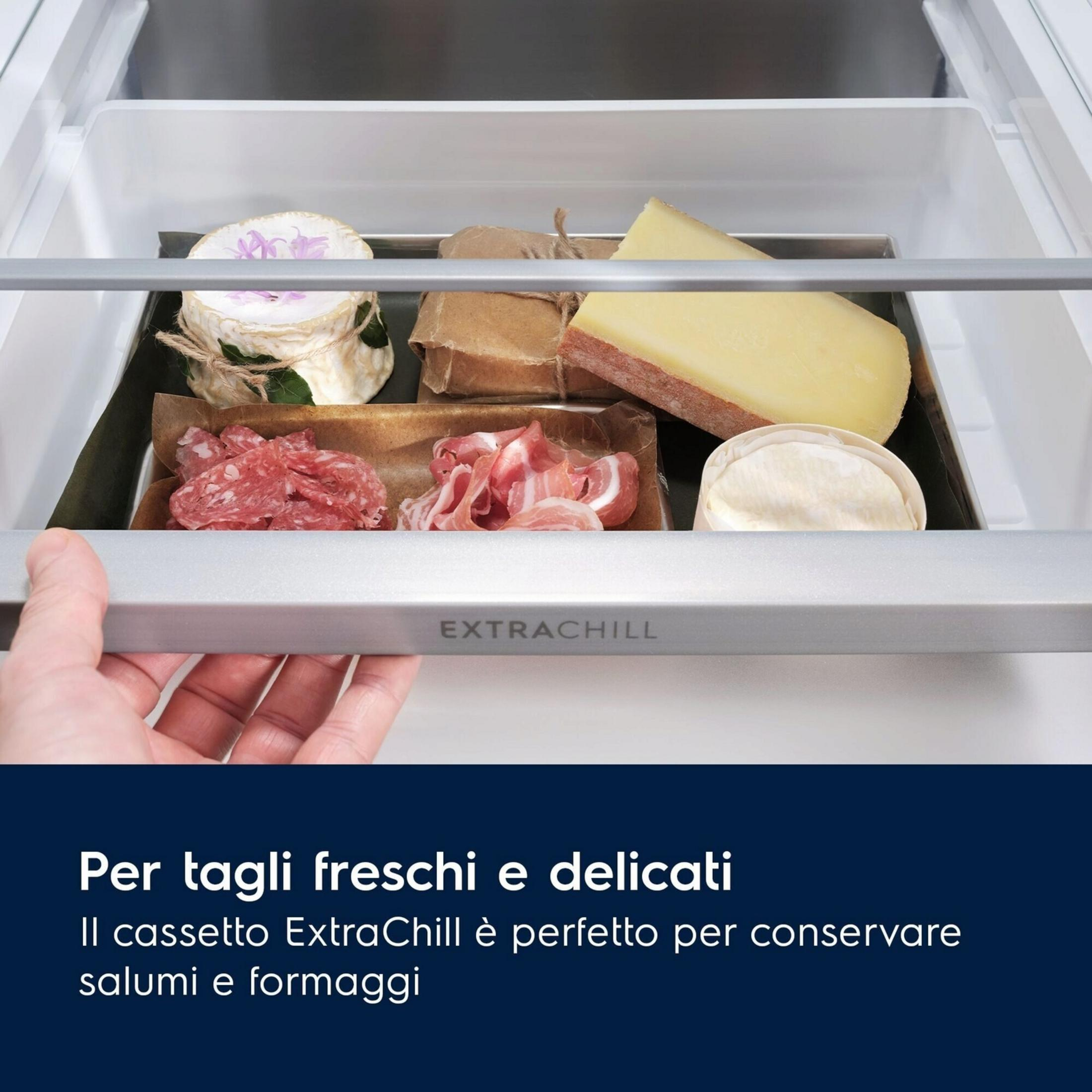 Un cassetto con formaggio, salumi e prosciutto viene aperto da una mano.