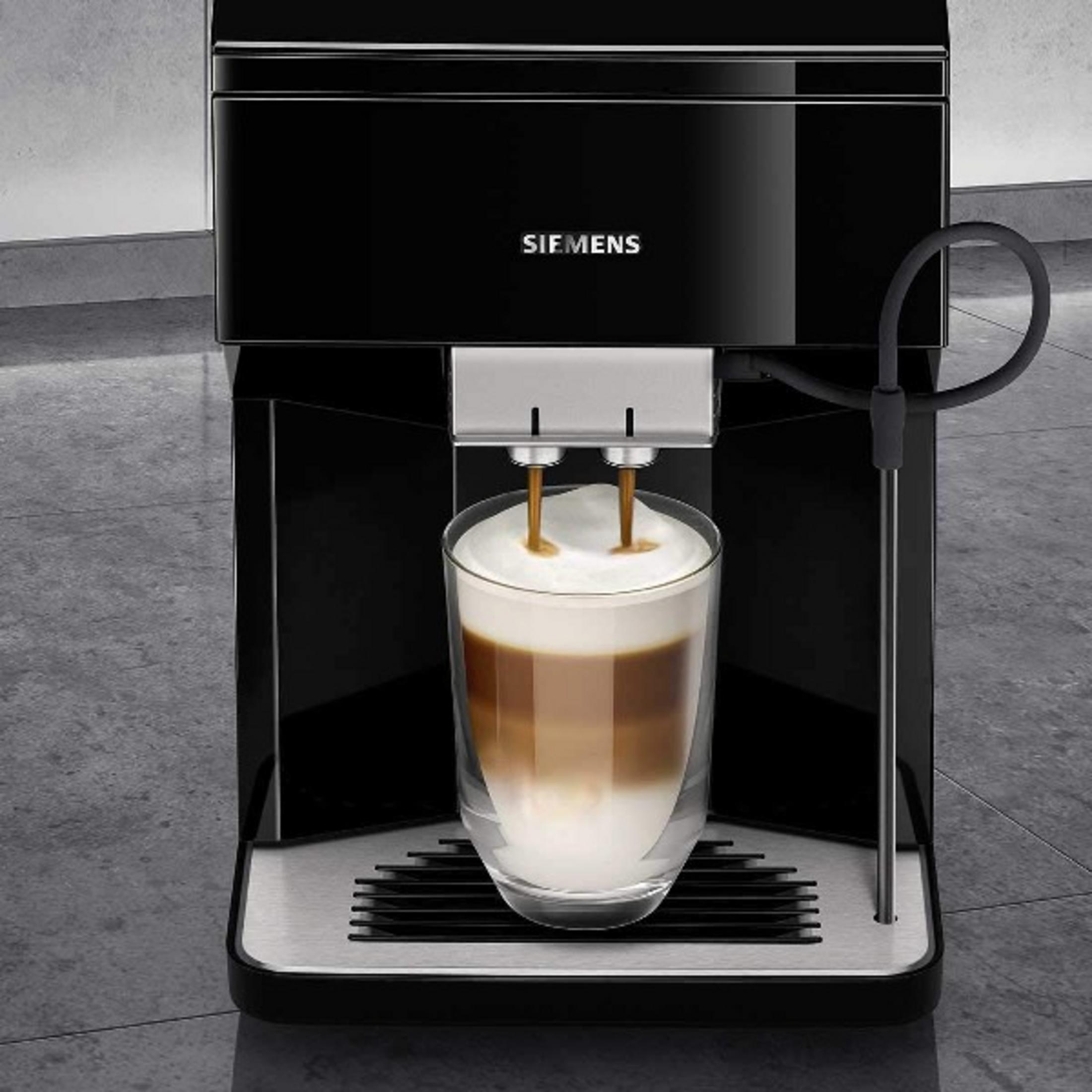 Een zwarte koffiemachine bereidt een latte macchiato in een glas voor.