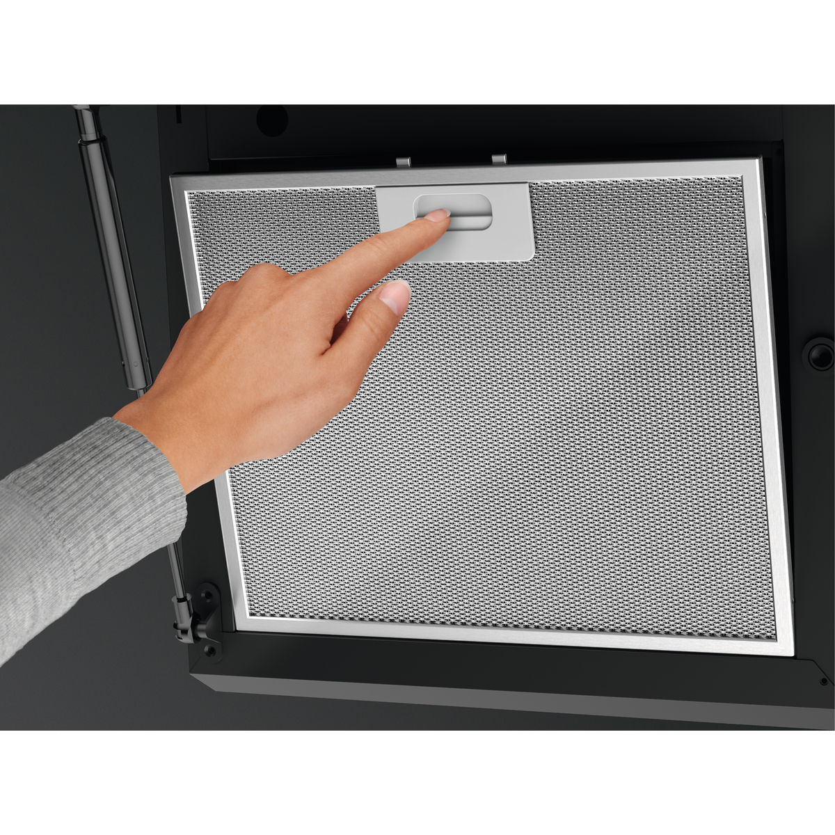 Eine Hand drückt einen Entriegelungshebel an einem Metallfilter.