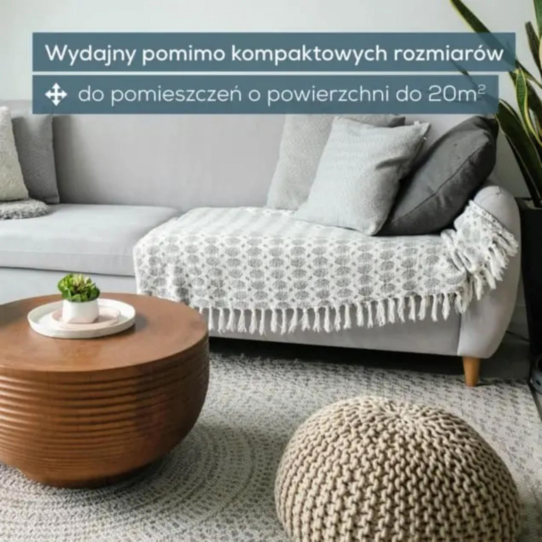 Modern living room with sofa, coffee table, and pouf. Gray and white textiles.