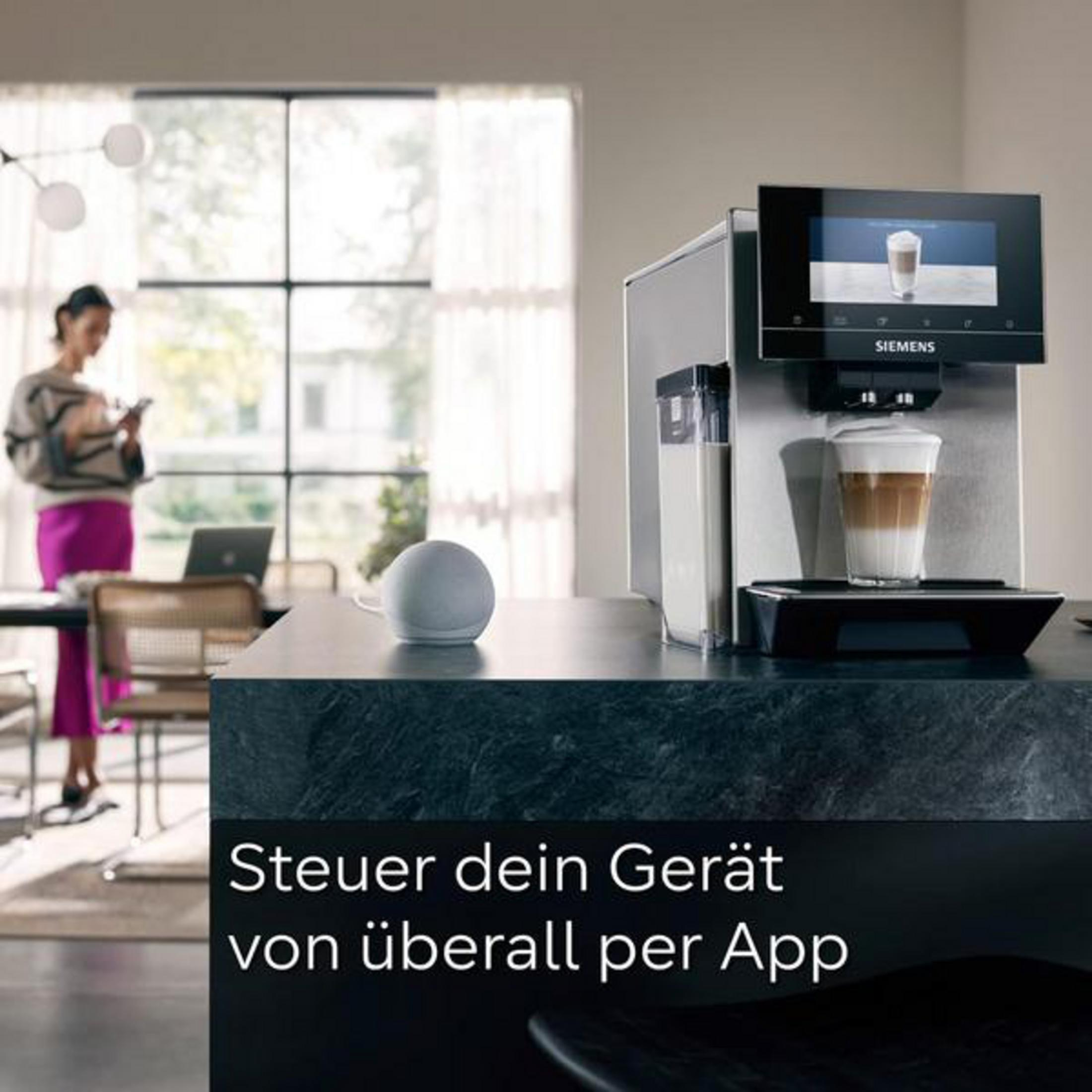 Macchina da caffè con latte e donna sullo sfondo con smartphone.
