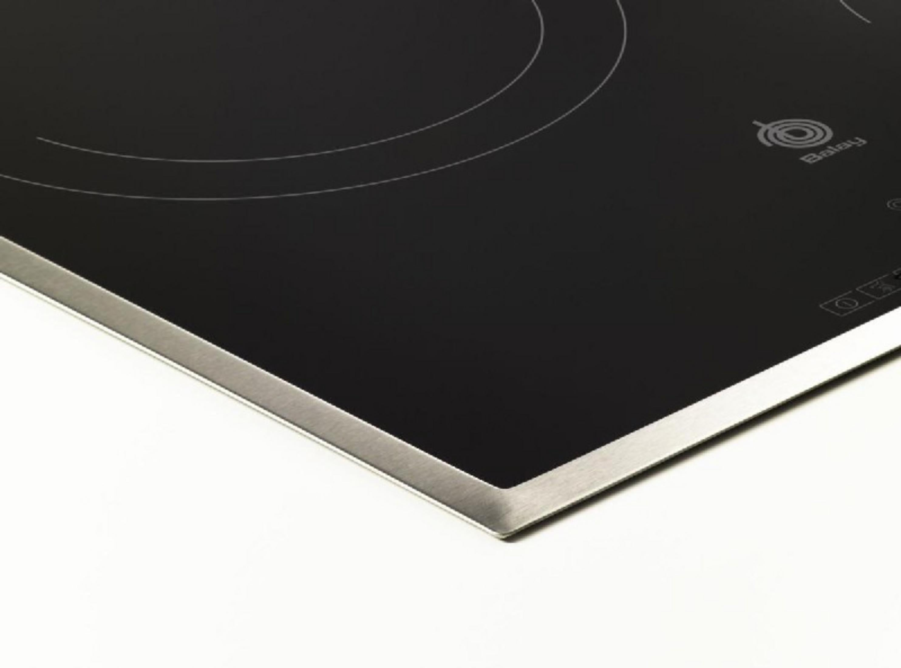 Primer plano de una placa de cocina negra con borde plateado y marcas de zona.