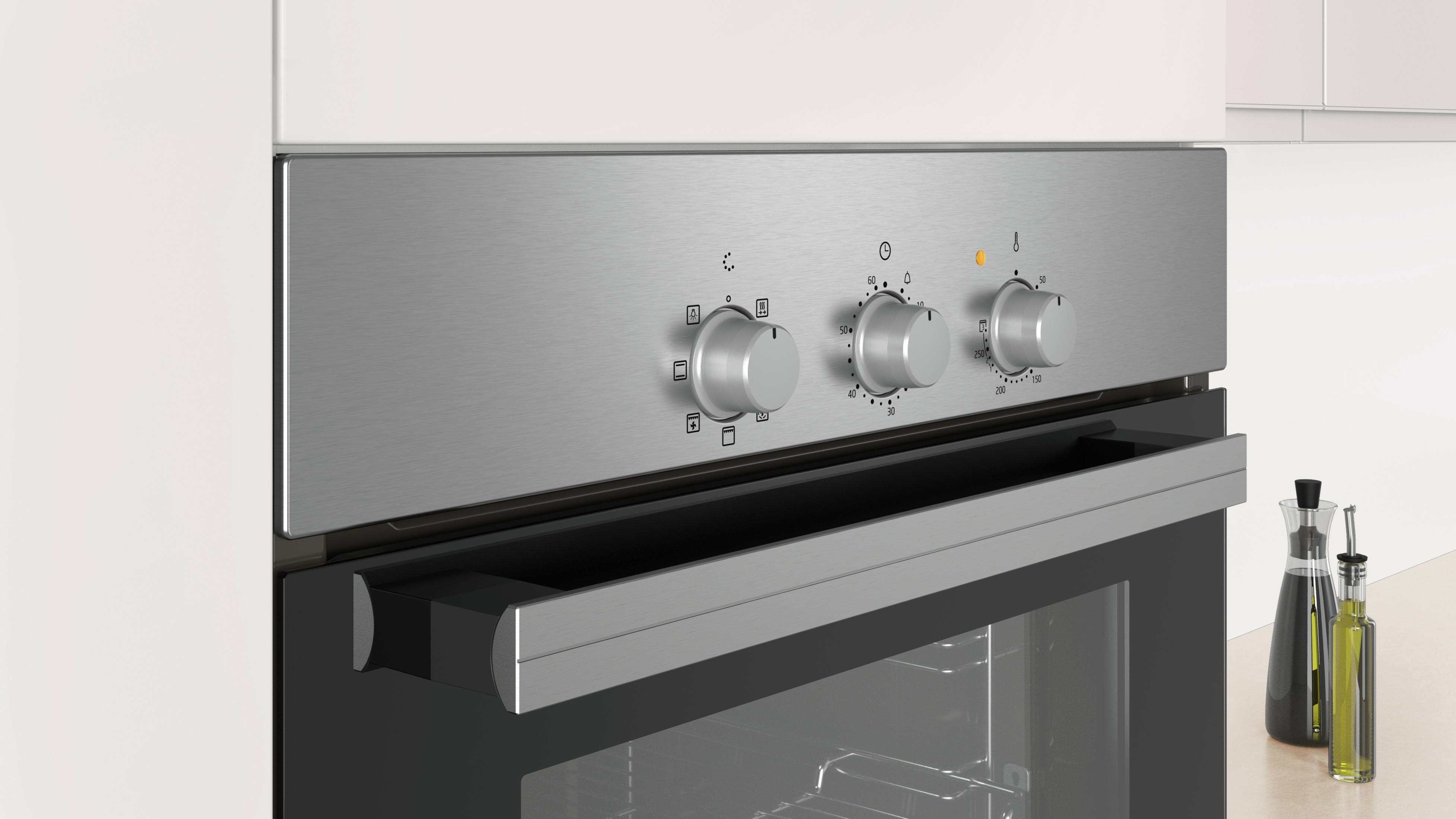 Un horno plateado moderno con tres mandos y un cajón.