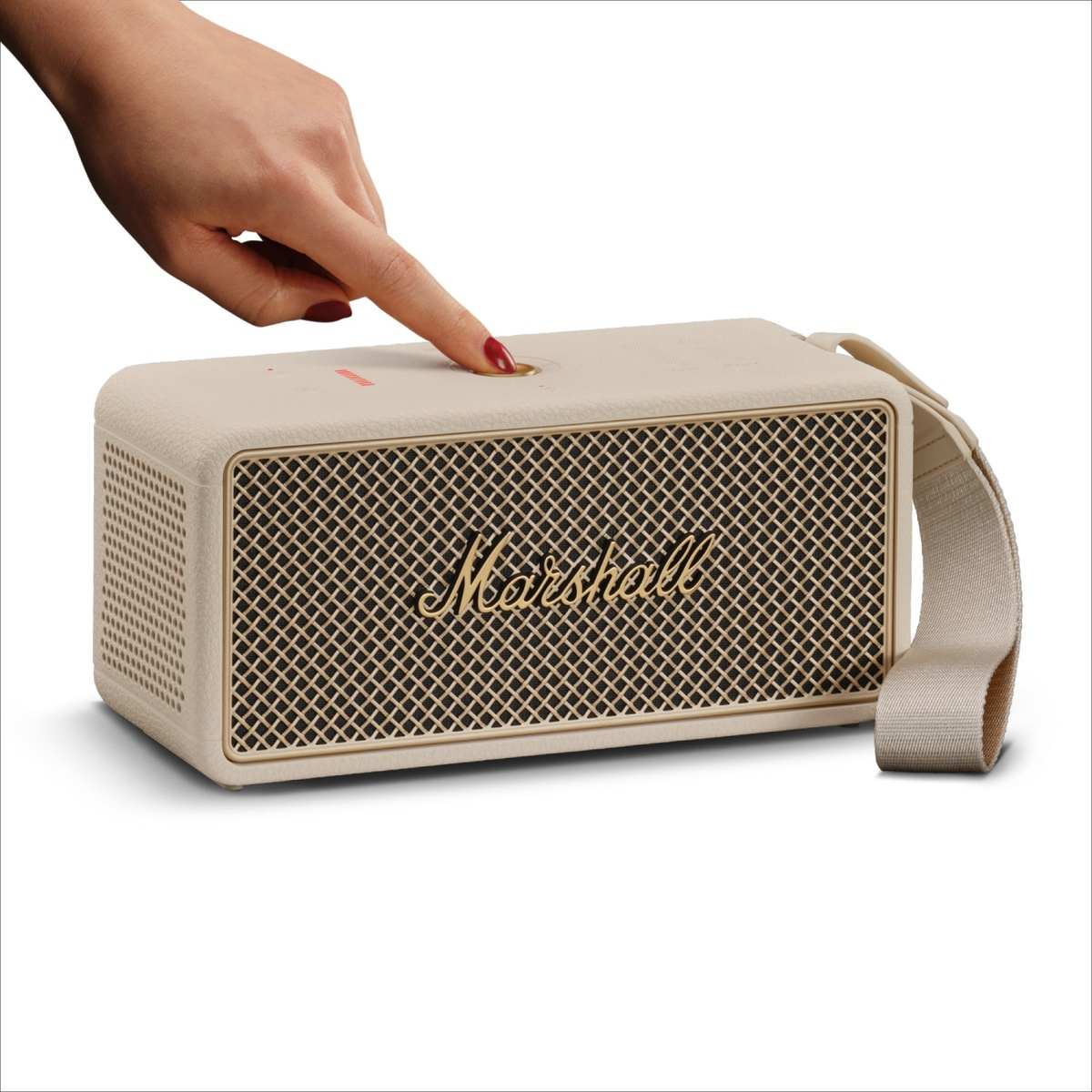 Eine Hand mit rotem Nagellack drückt einen Knopf an einem beigen Marshall-Lautsprecher mit goldenem Logo.