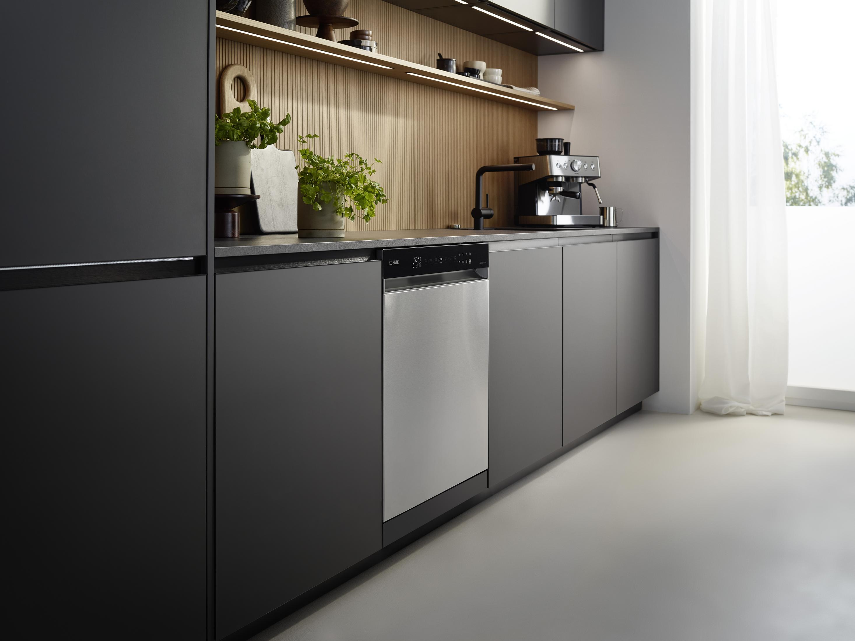 Moderne Küche mit dunklen Schränken, Spülmaschine, Kaffeemaschine und Pflanzen.
