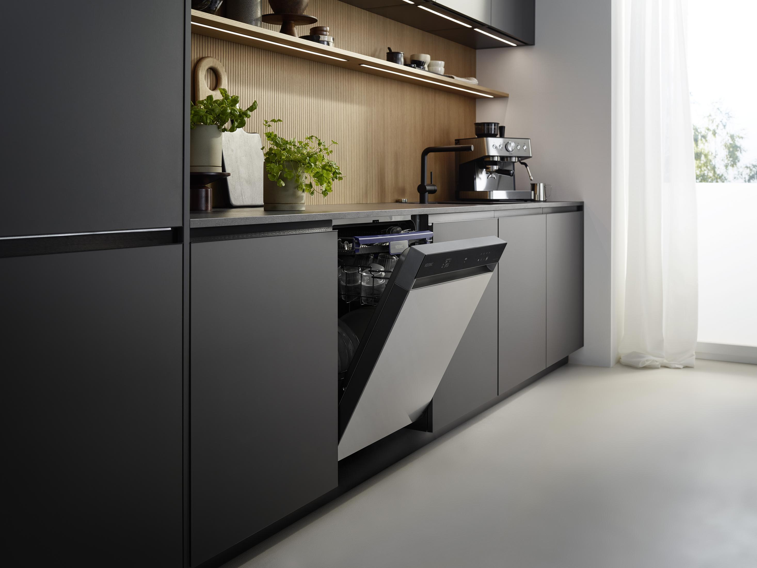 Moderne Küche mit geöffnetem Geschirrspüler, Espressomaschine und Pflanzen.