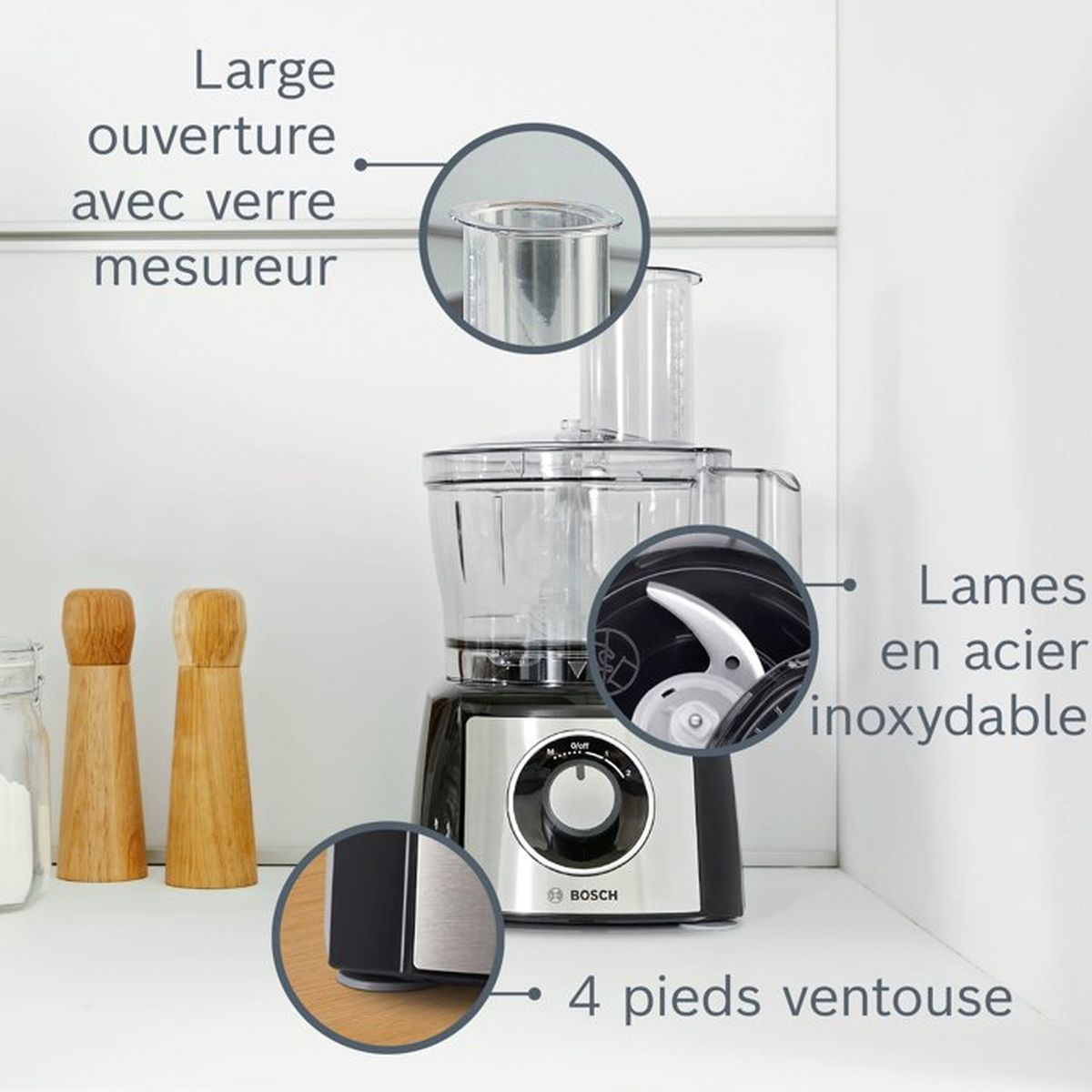 A food processor with a measuring cup lid, stainless steel blades, and suction feet.