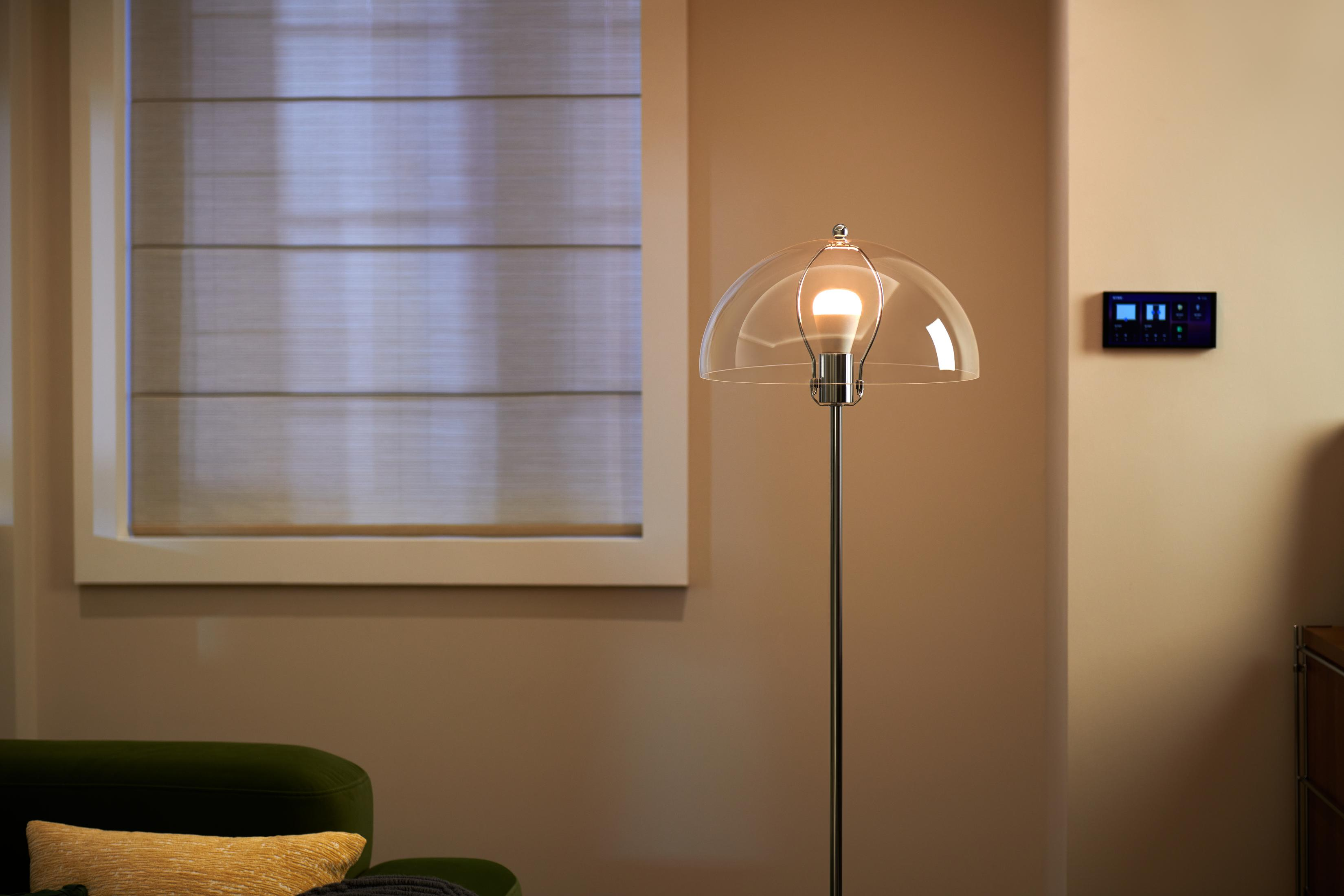 Una lámpara de pie moderna con cúpula de cristal junto a una ventana con persianas.