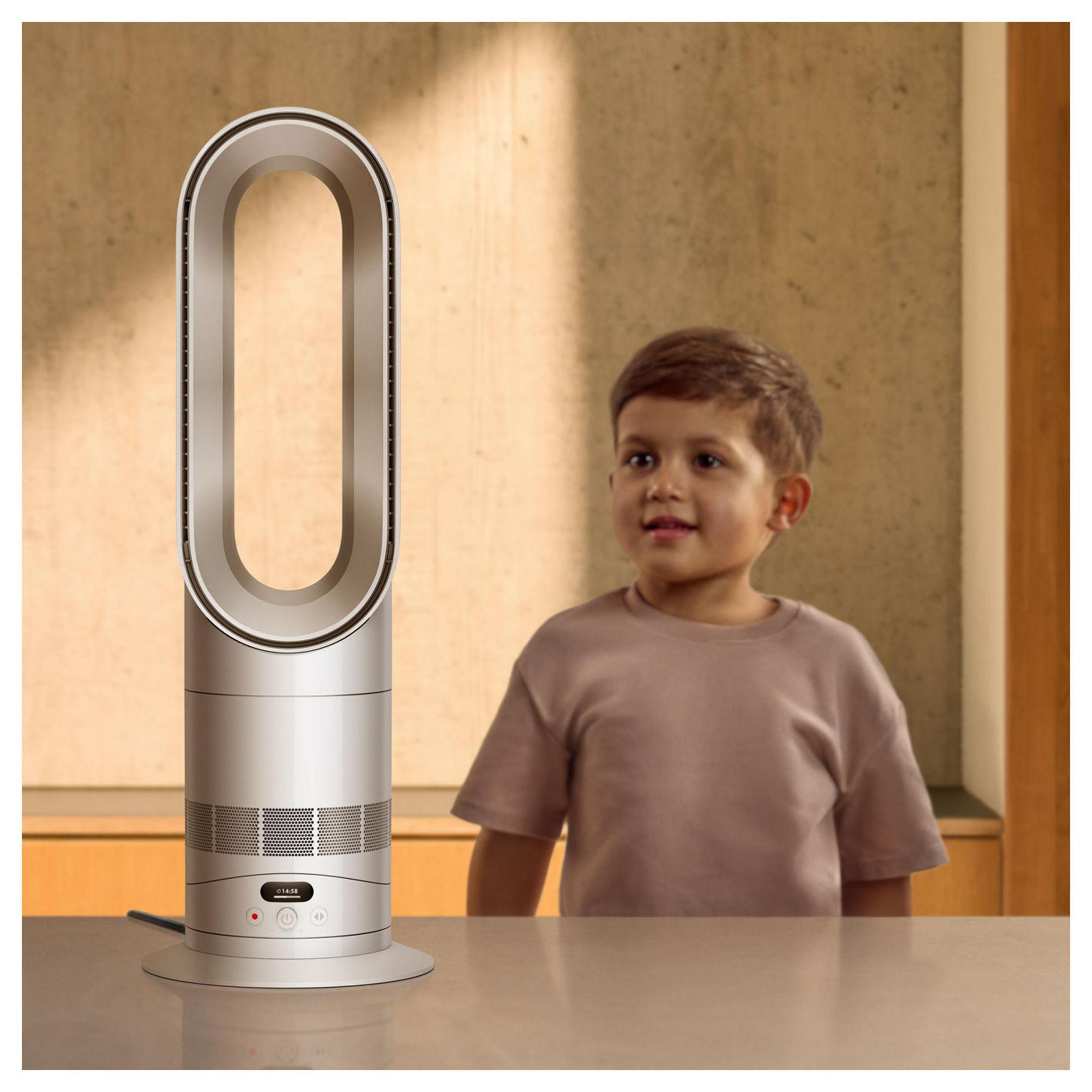 Ein Junge steht neben einem silbernen Turmventilator mit einem ovalen Luftkanal.
