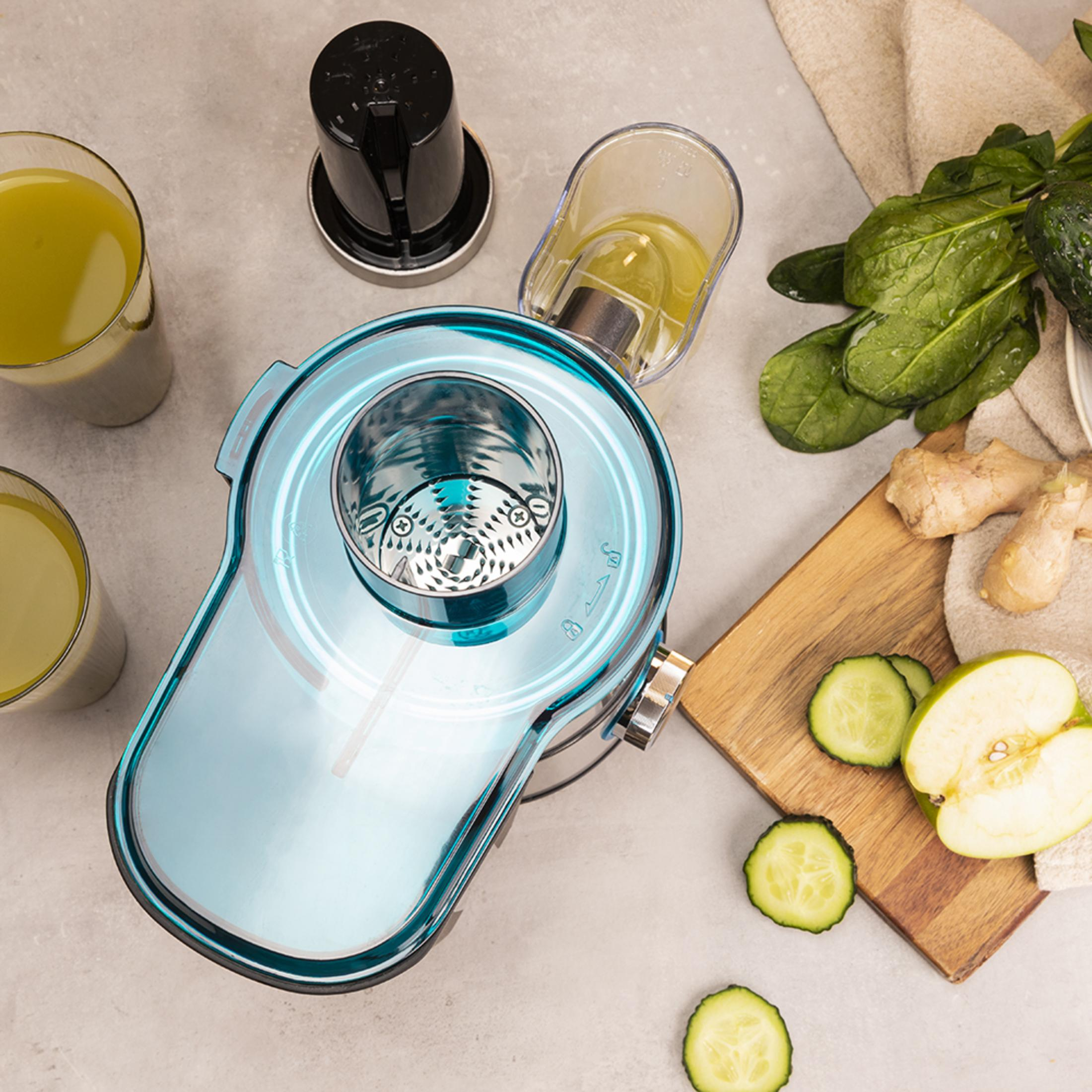 Un exprimidor azul con dos vasos de jugo e ingredientes frescos.