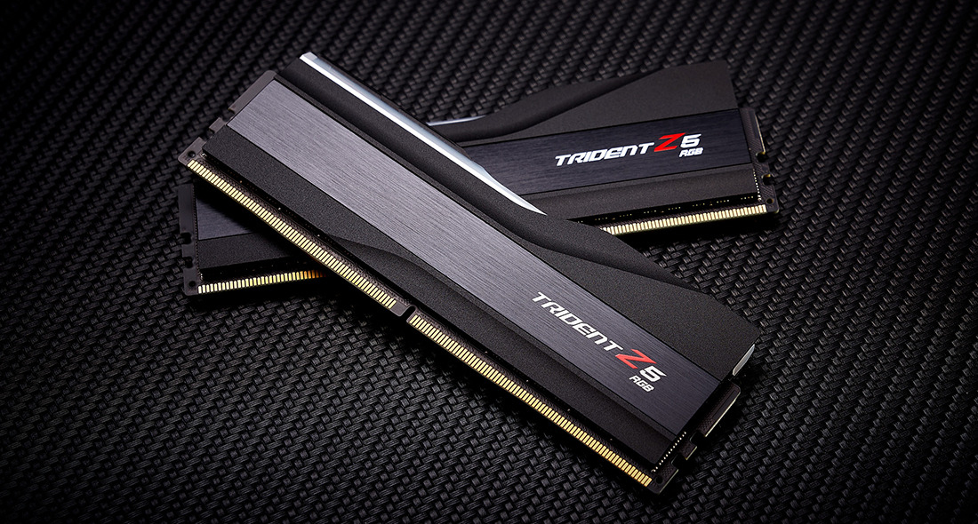 Due moduli RAM Trident Z5 RGB neri giacciono diagonalmente su un motivo in carbonio nero.