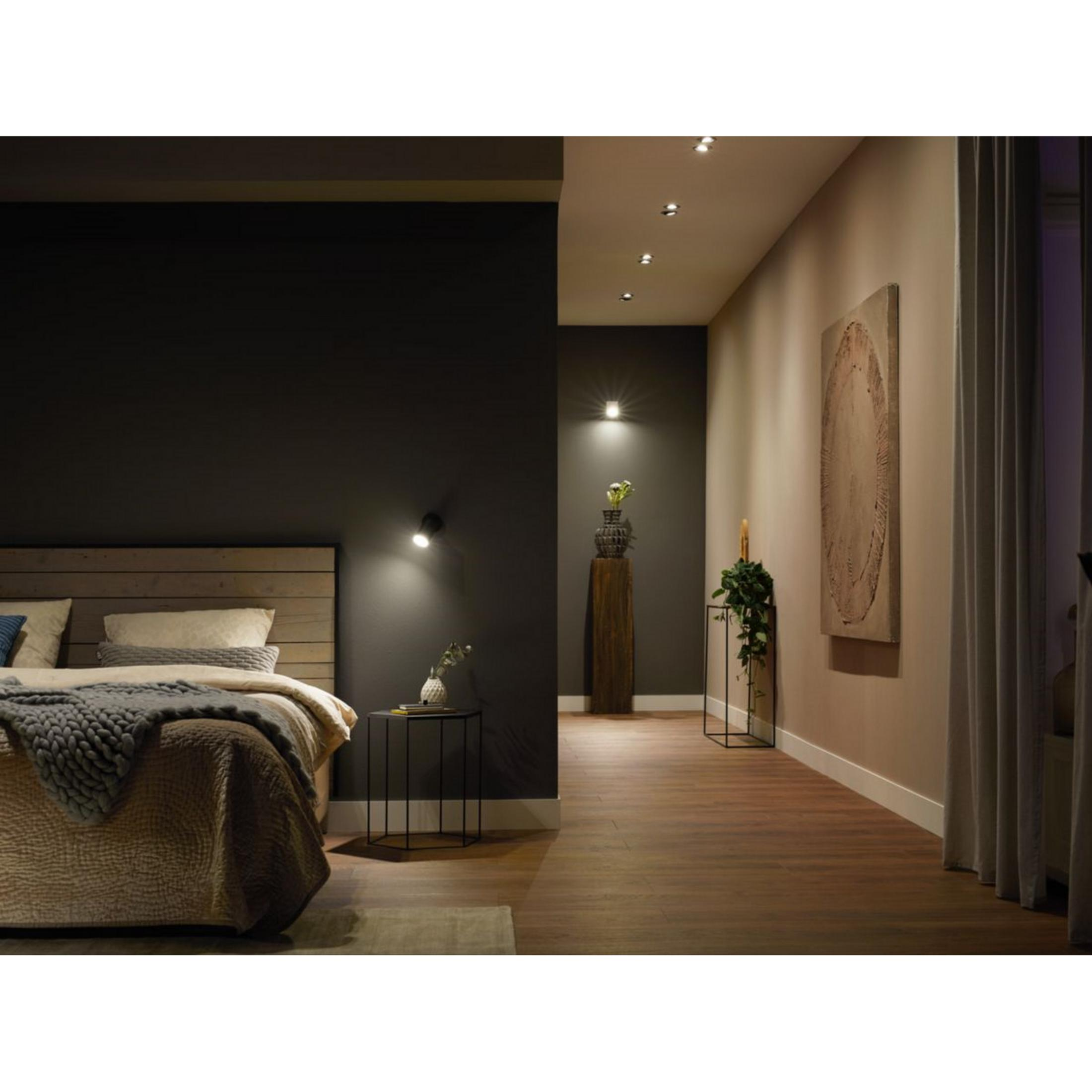 Une chambre avec lit en bois et mur sombre à côté d'un couloir avec une œuvre d'art.